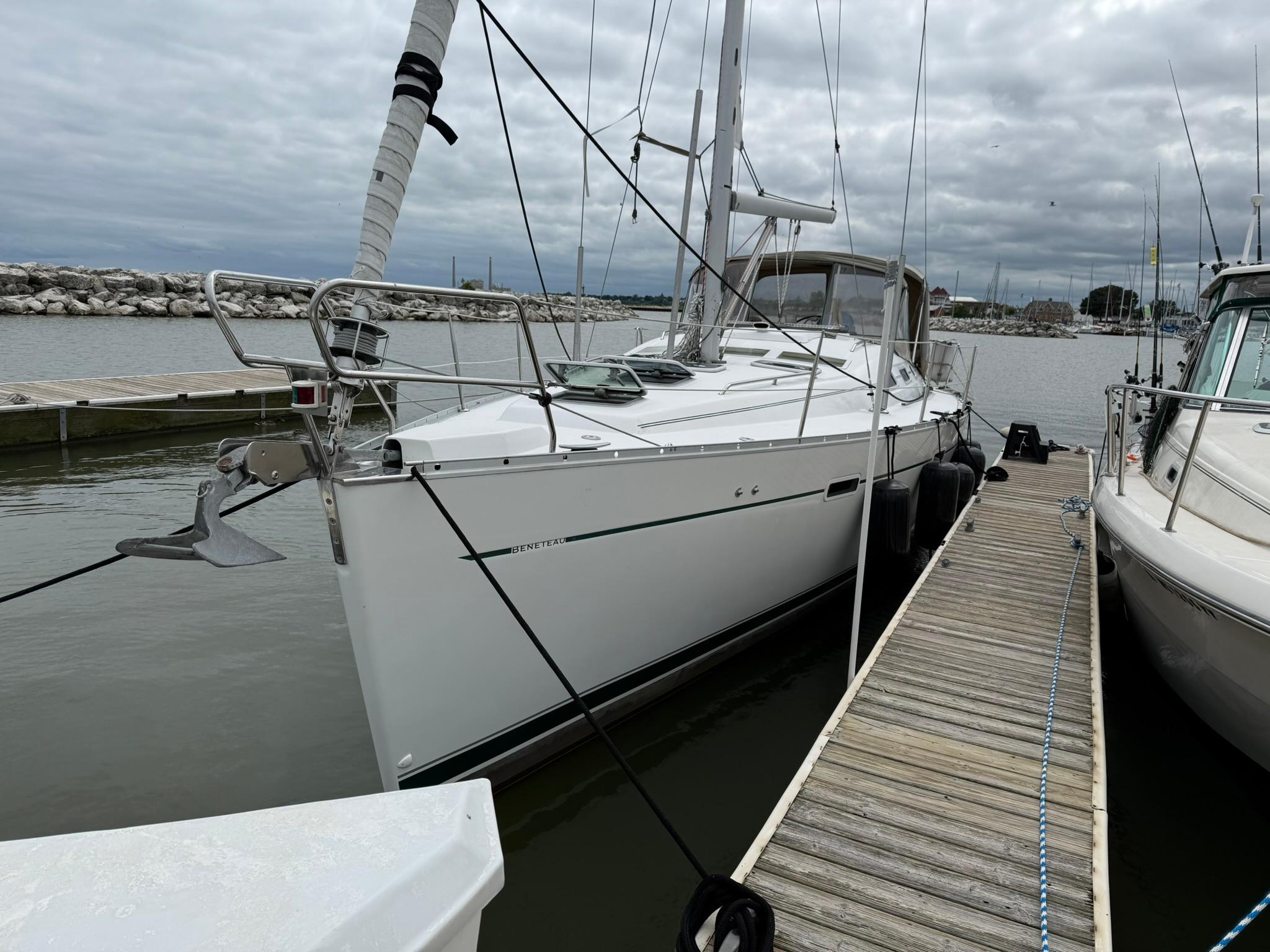 2003 Beneteau 393 sailboat docked at a marina under cloudy skies.