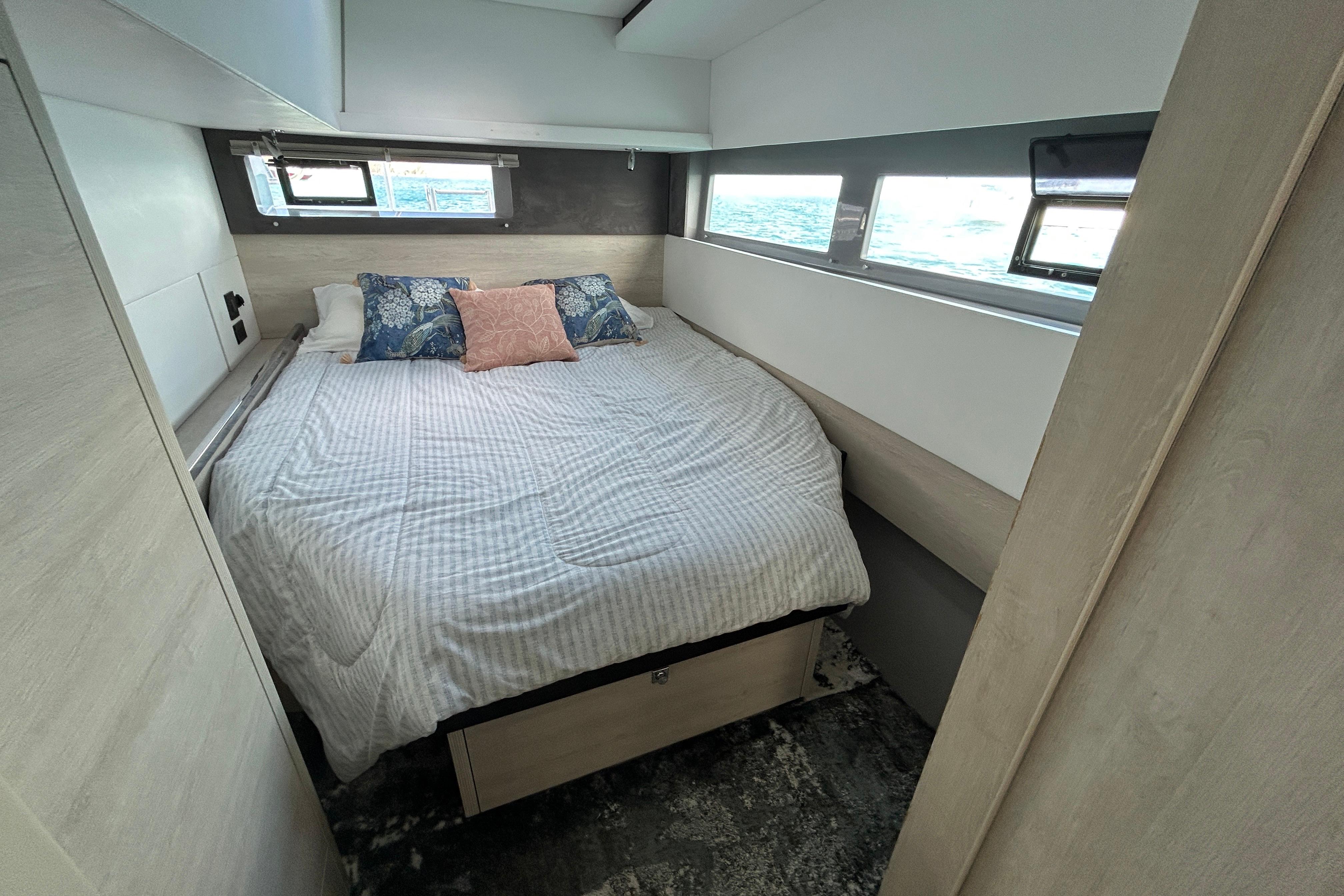 Cozy bedroom in a 2020 Leopard 45 yacht with ocean view windows.