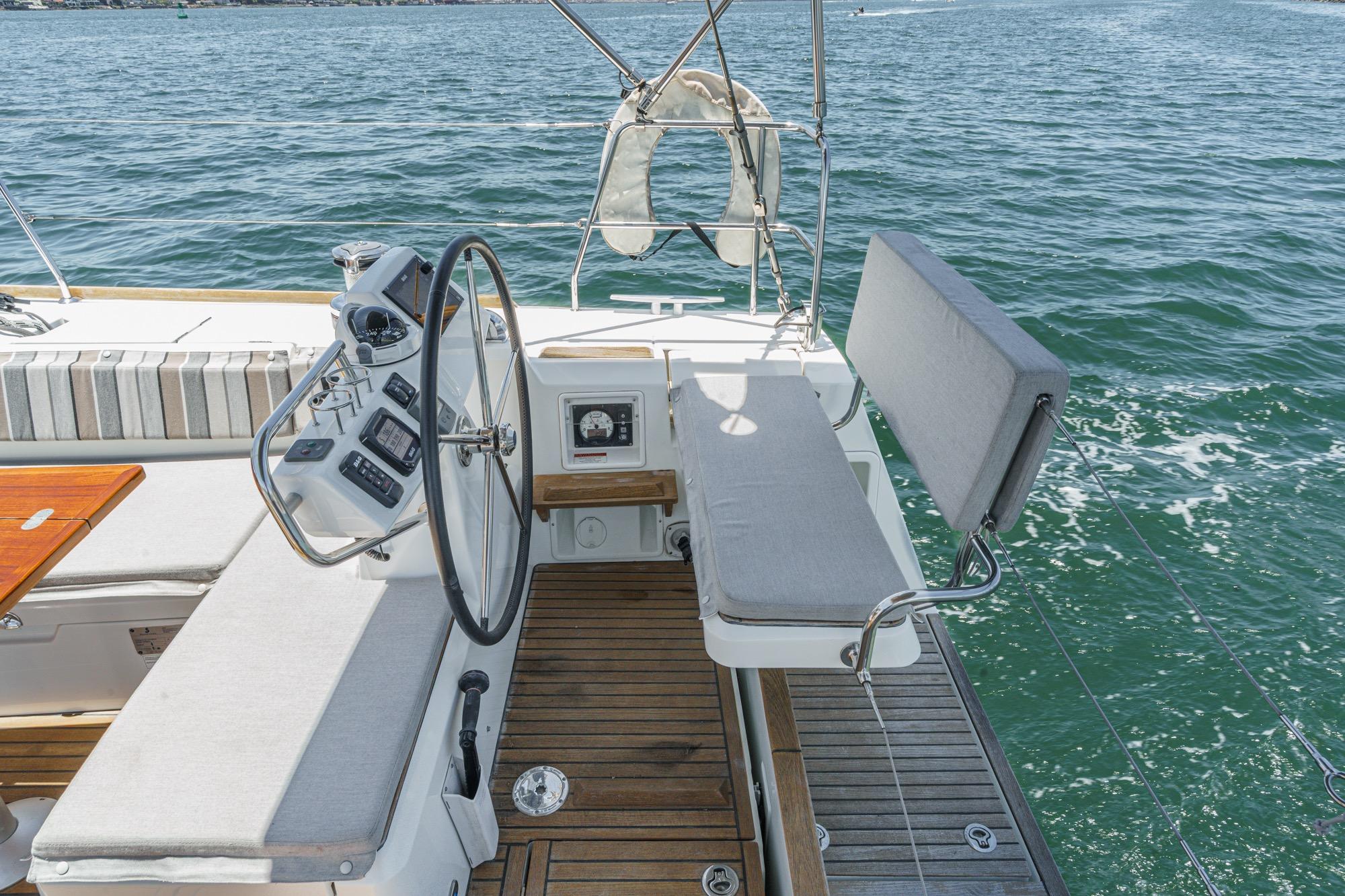 2017 Beneteau Sense 50 yacht cockpit with steering wheel, cushioned seating, and ocean view.