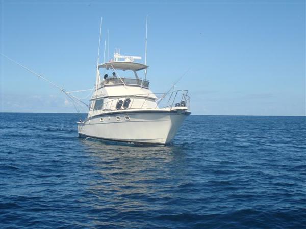 1985 Hatteras 45 Convertible yacht on open sea under clear blue sky.