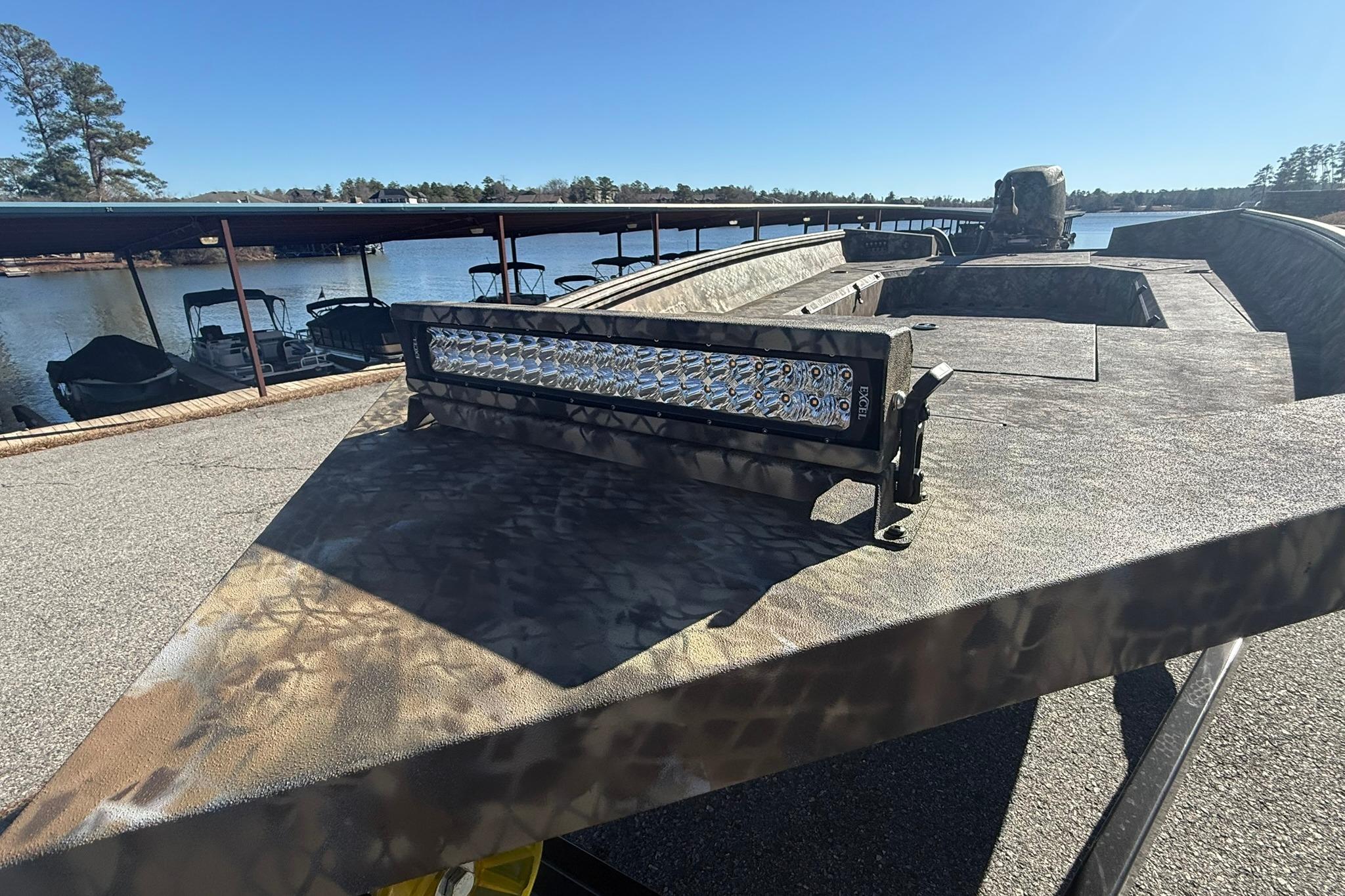 Camouflage-patterned Excel 183 Tomahawk boat, 2026 model, docked by a serene lake.