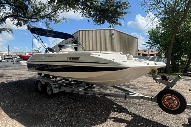 1999 Hurricane SunDeck Sport 201 OB boat on trailer, parked outdoors under a blue sky.