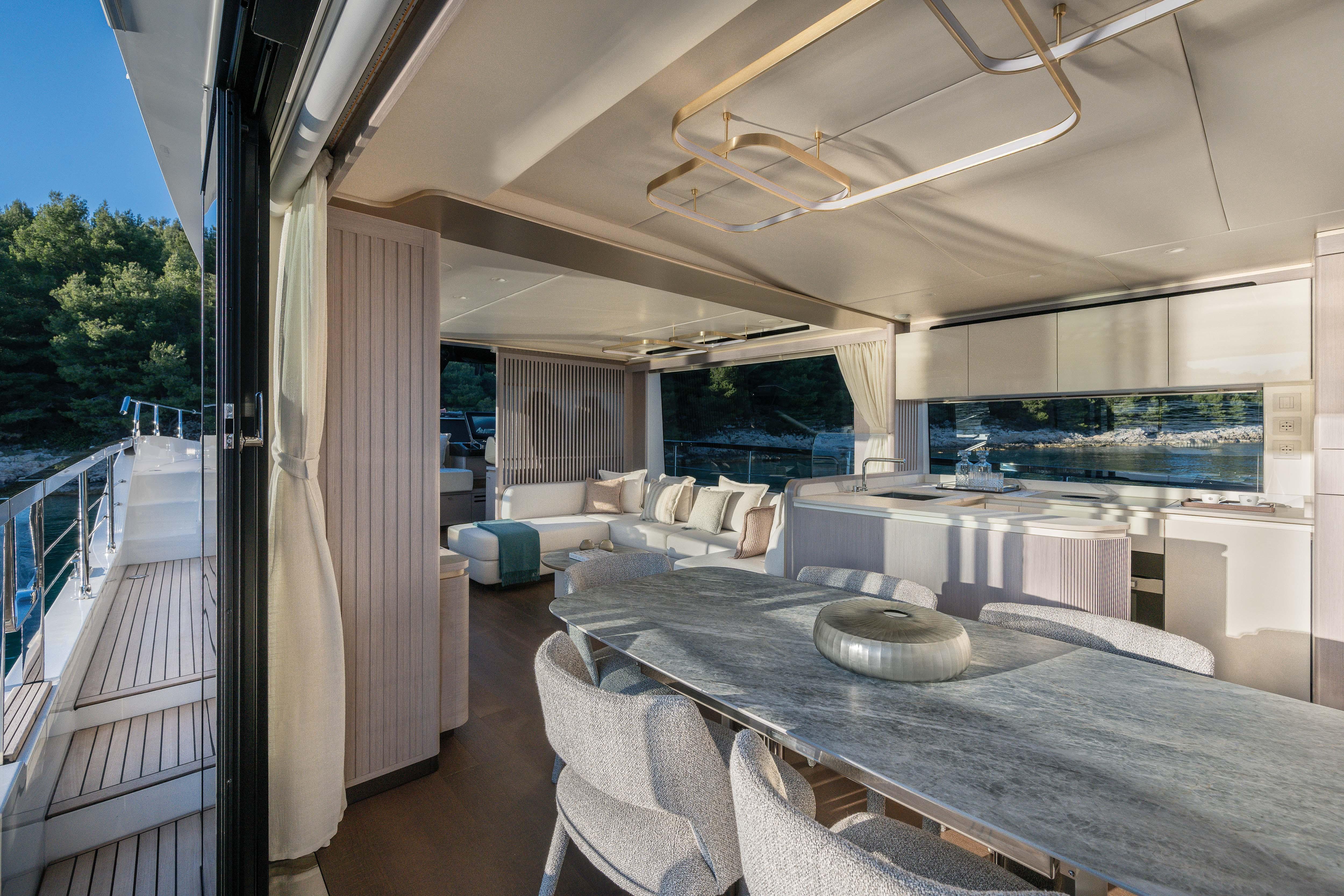 Luxurious yacht interior with dining area and lounge, surrounded by water and trees.
