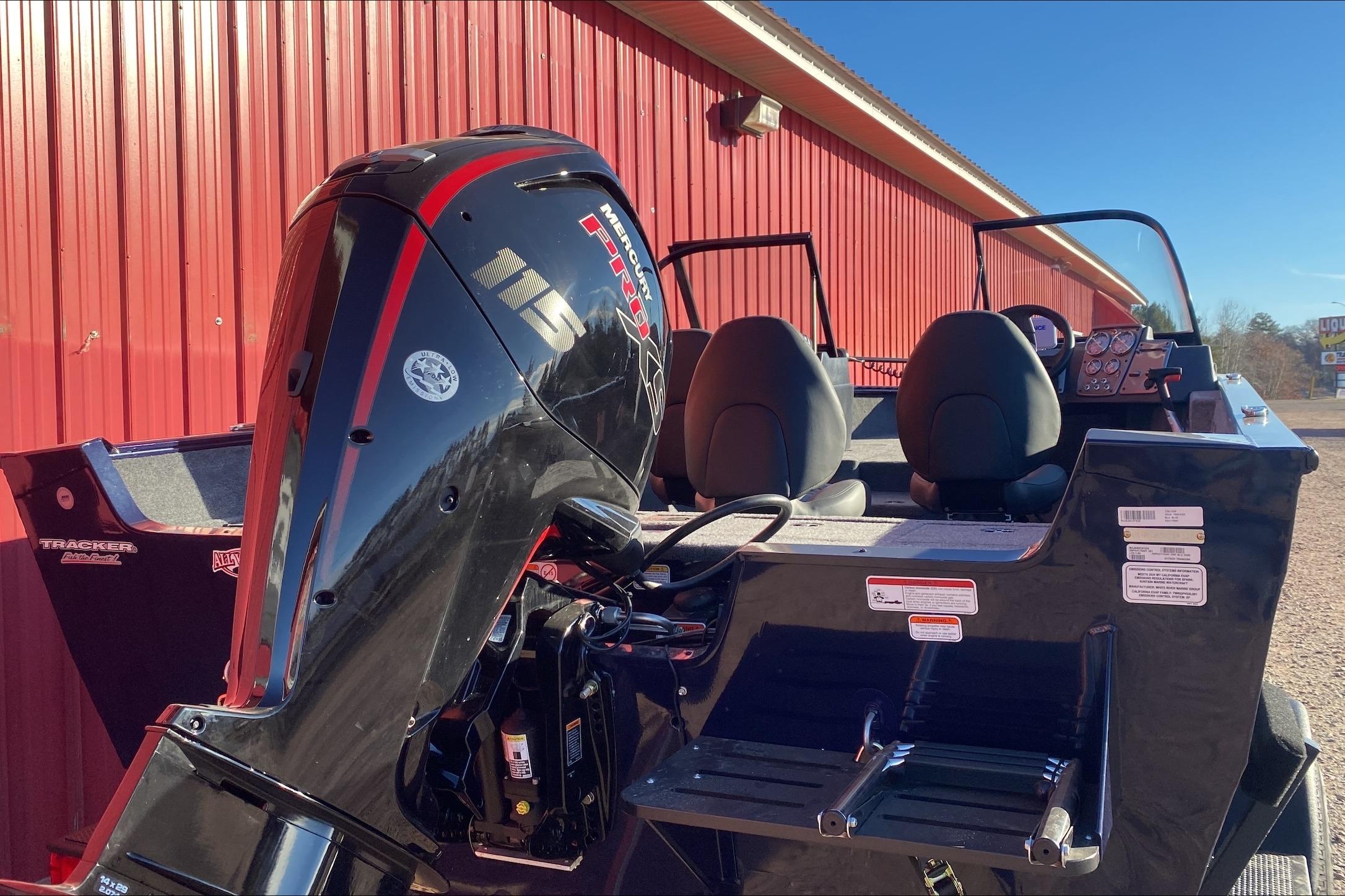 2026 Tracker Pro Guide V-175 WT boat with Mercury 115 engine, parked by a red building.