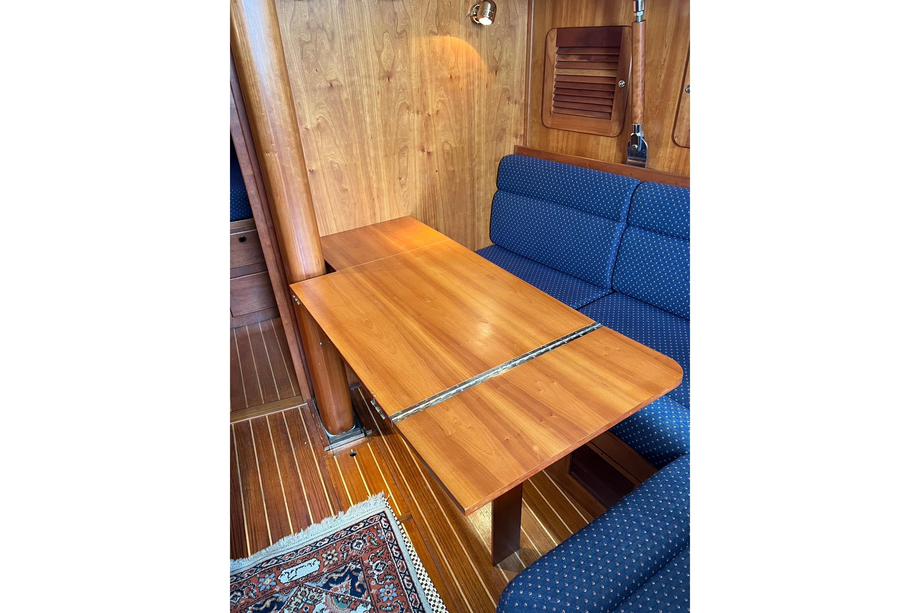 1998 Sabre 362 yacht interior with wooden table and blue cushioned seating.