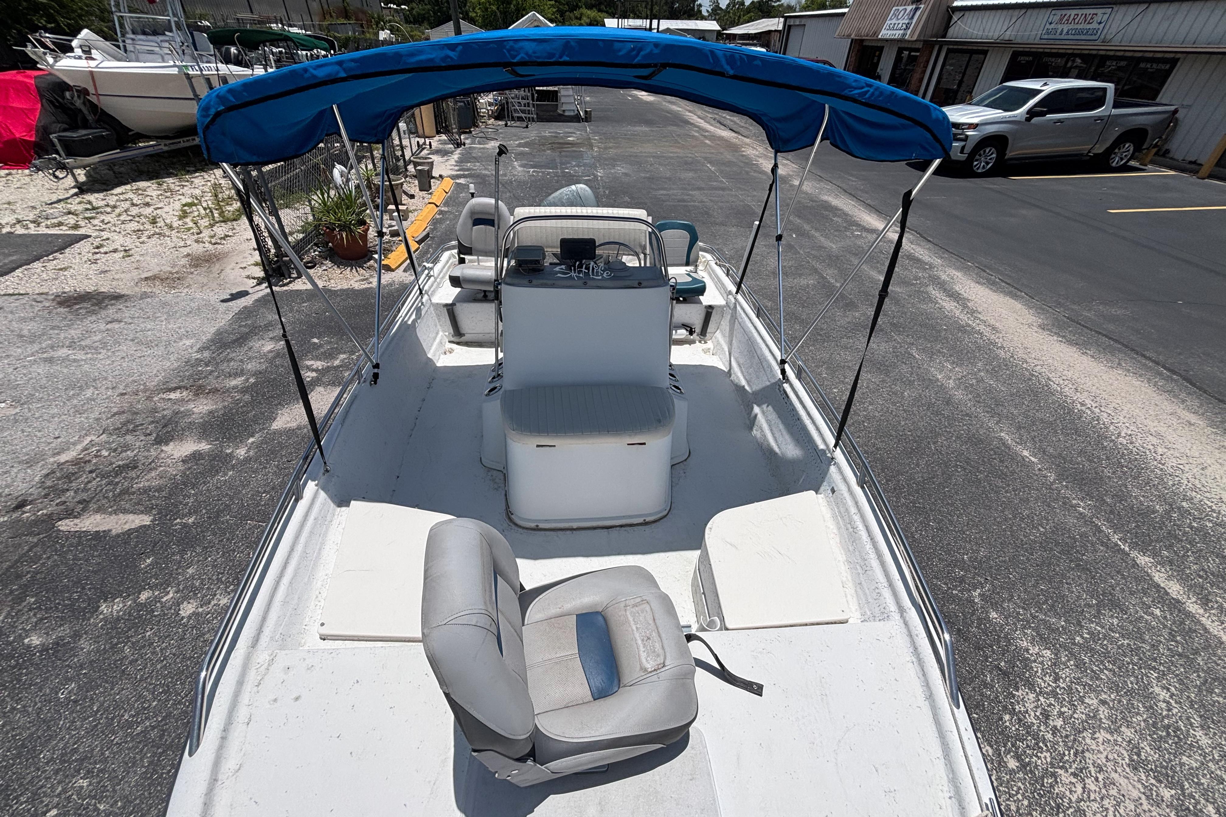 2000 VIP 1880 BAY STEALTH boat with blue canopy, parked on asphalt.
