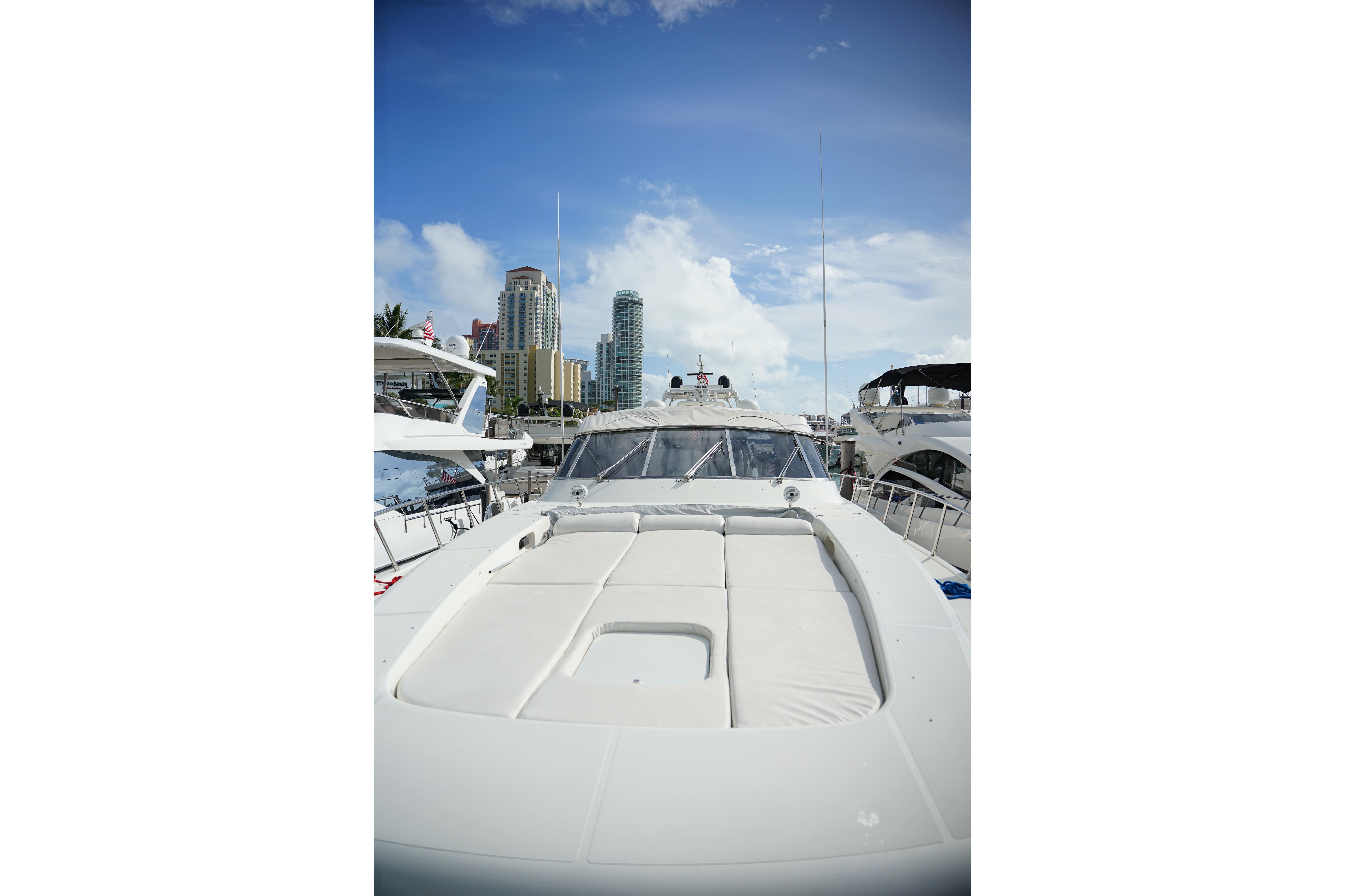 1999 Mangusta 80 yacht docked with city skyline in background.