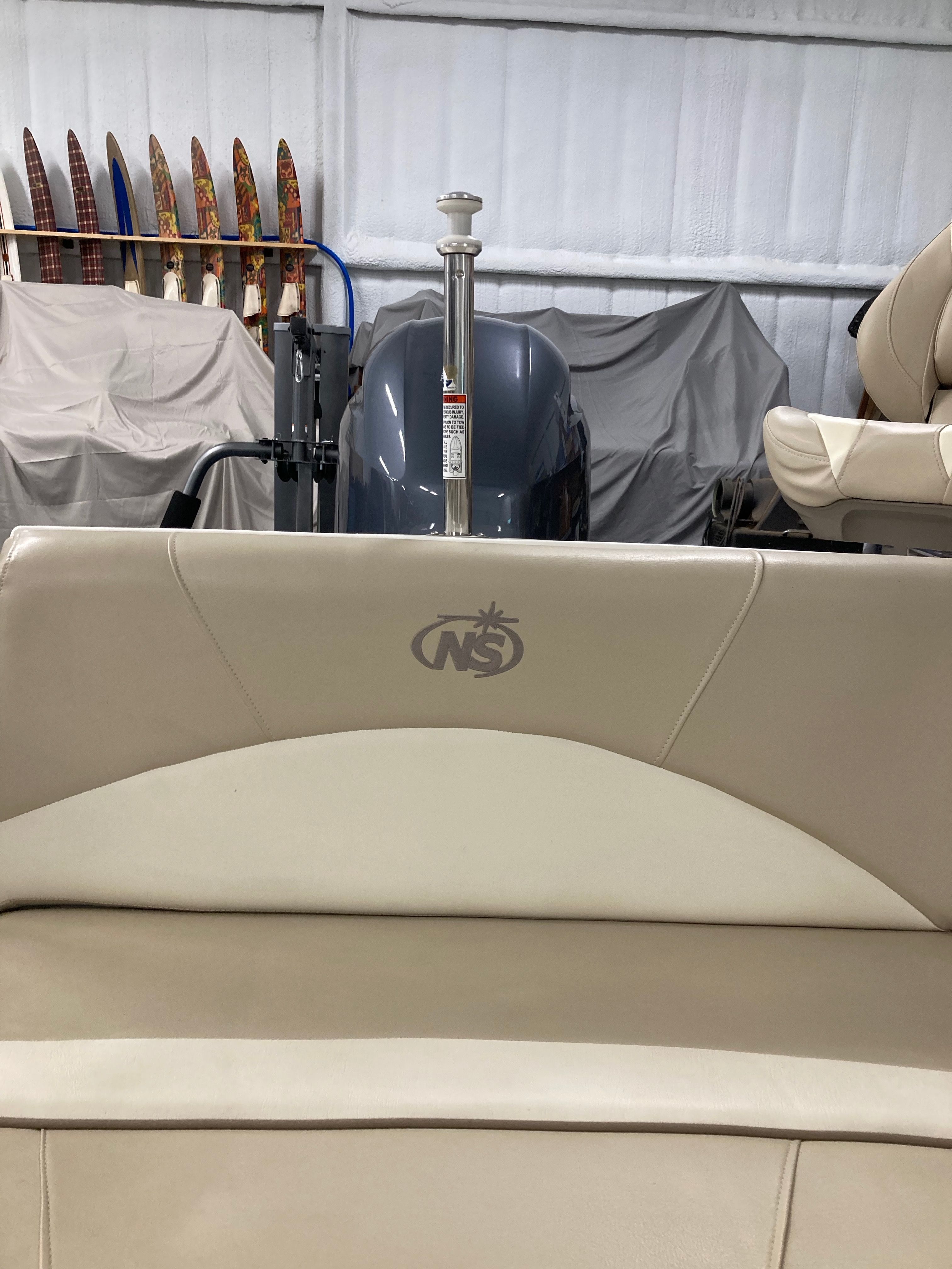 Interior view of a boat with beige seating and an engine in the background.