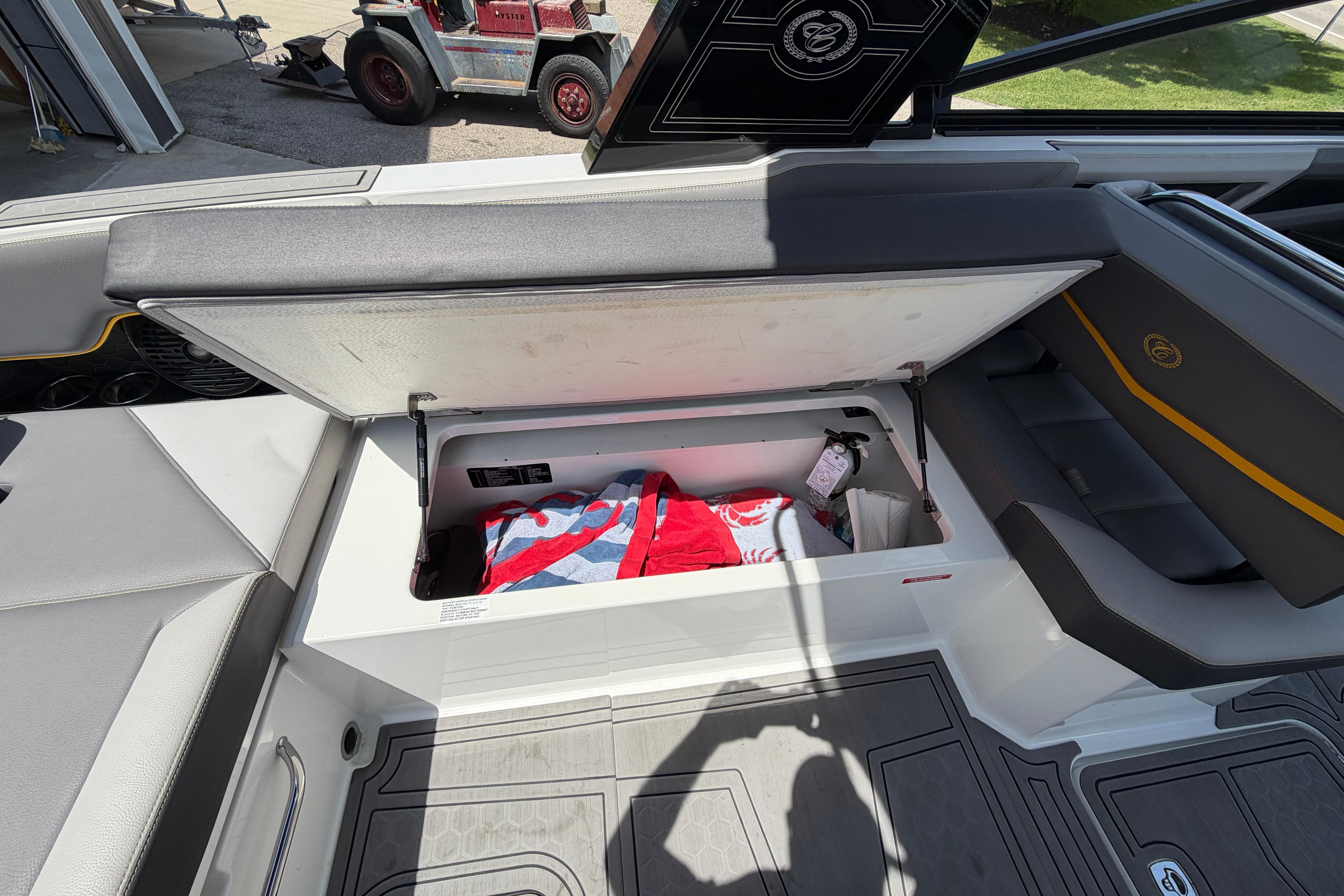 2021 Cobalt R8 Surf boat interior storage compartment with open lid, revealing towels inside.