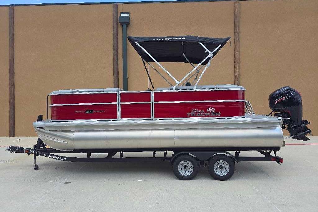 2026 Sun Tracker Party Barge 20 DLX pontoon boat with red exterior and black canopy.