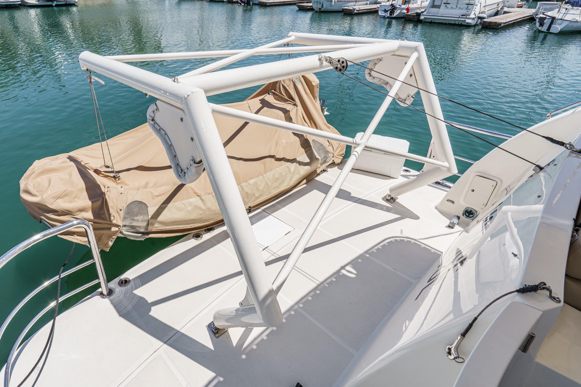 2003 McKinna 65 Pilothouse yacht deck with covered dinghy and marina view.