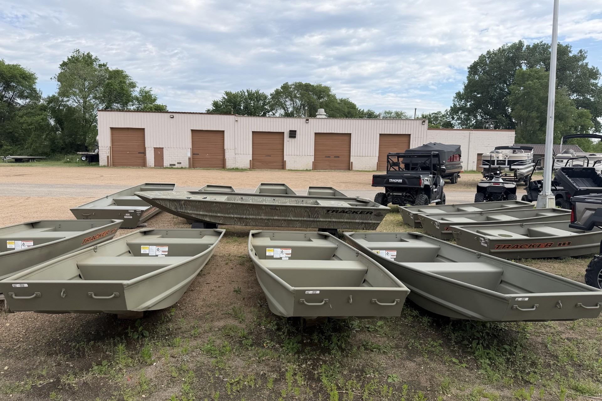 2026 Tracker Grizzly 14 Jon boats displayed outdoors near a warehouse.