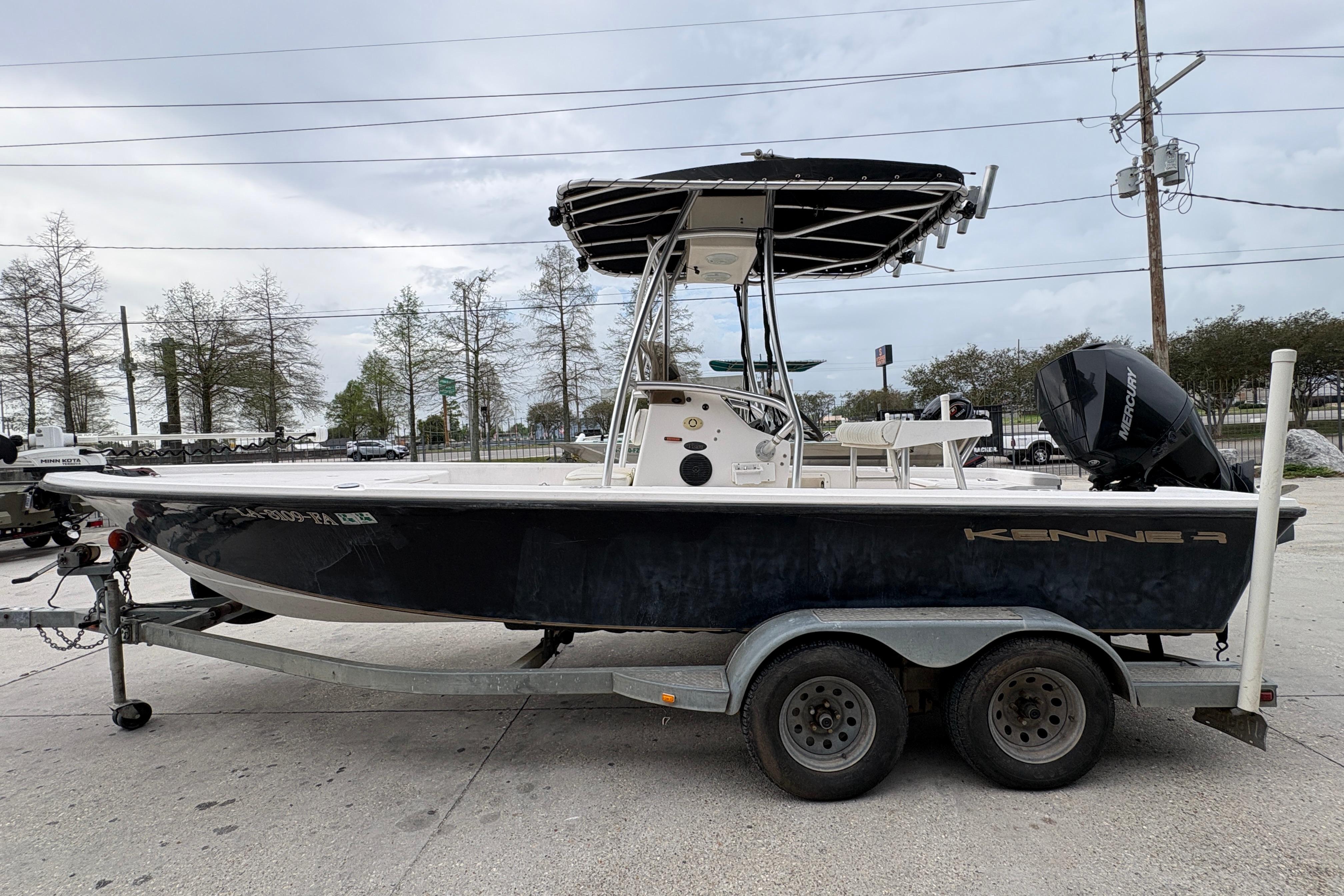 2000 Kenner 21 VISION boat on trailer with Mercury engine, parked outdoors.