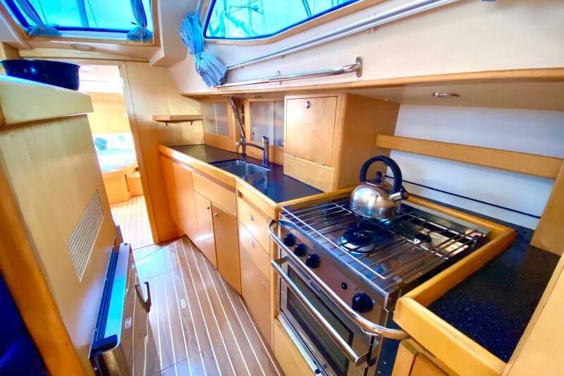 Galley kitchen in 2009 Southerly 49 yacht with stove, sink, and wooden cabinetry.