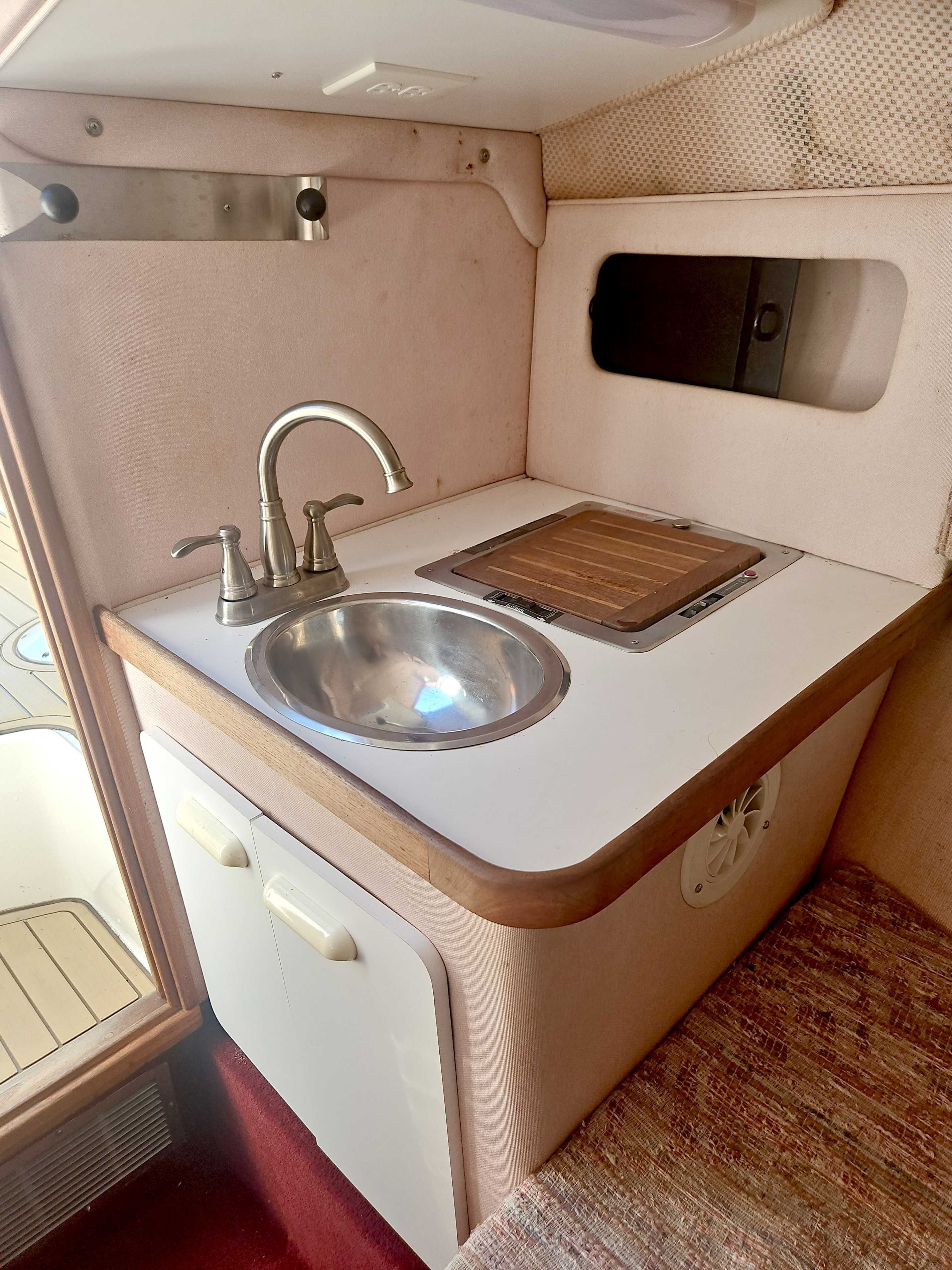 Small kitchenette with sink and stove in a boat.