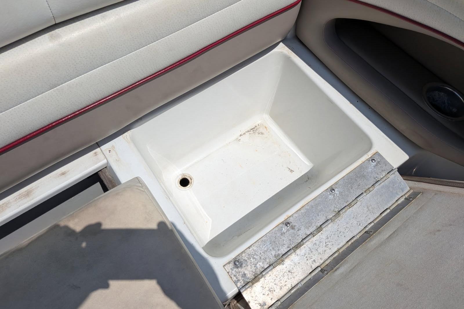 Storage compartment in a 2020 Cobalt 206 boat, featuring cushioned seating and a drain plug.