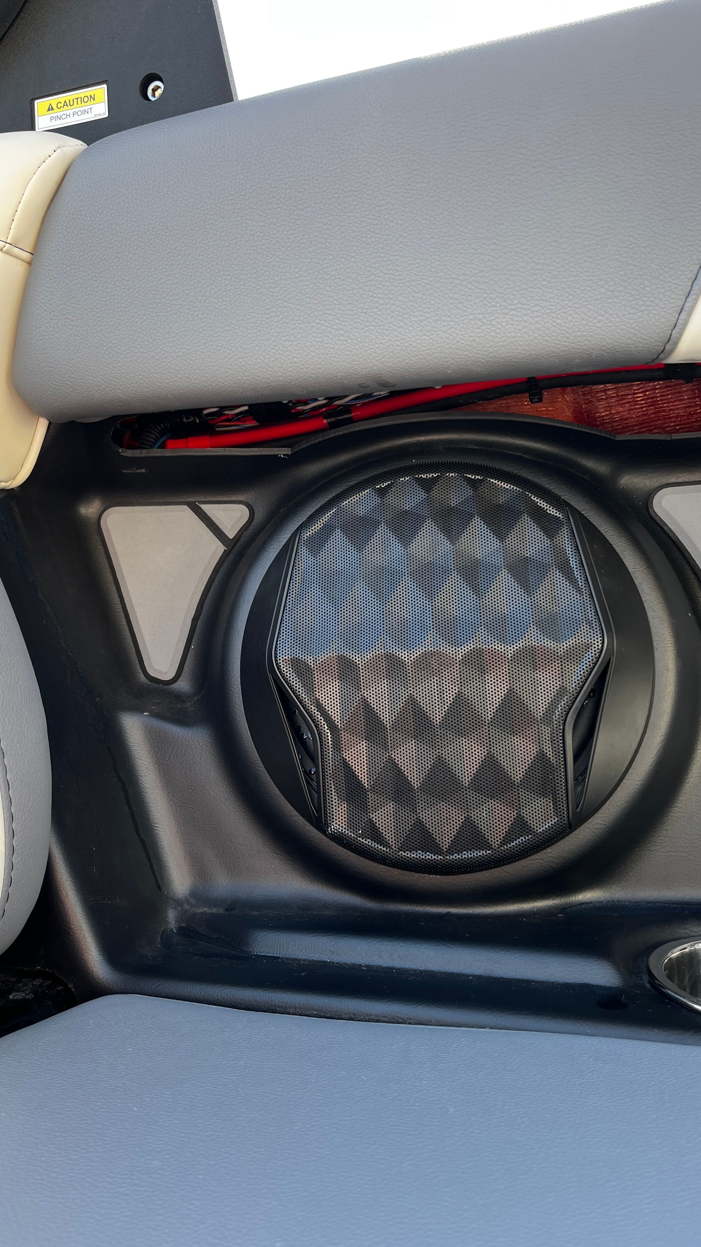 Close-up of a speaker in a boat with gray upholstery.