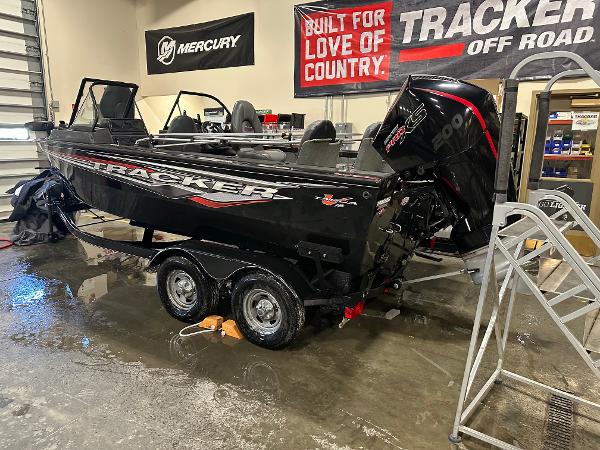 2023 Tracker Targa V-18 WT boat in showroom, featuring Mercury engine and promotional banners.