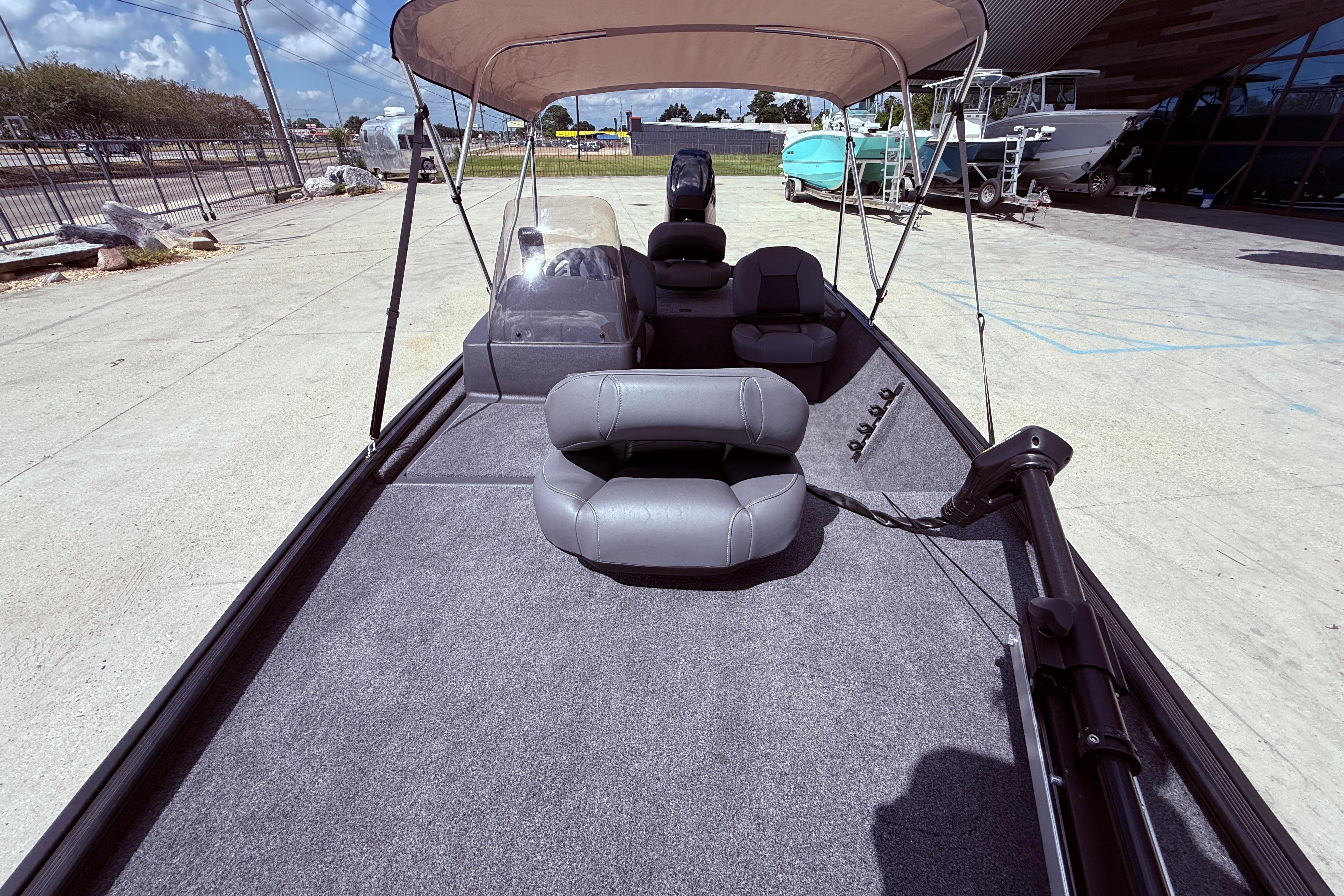 2025 Bass Tracker Classic XL boat interior with seating and canopy, parked outdoors.