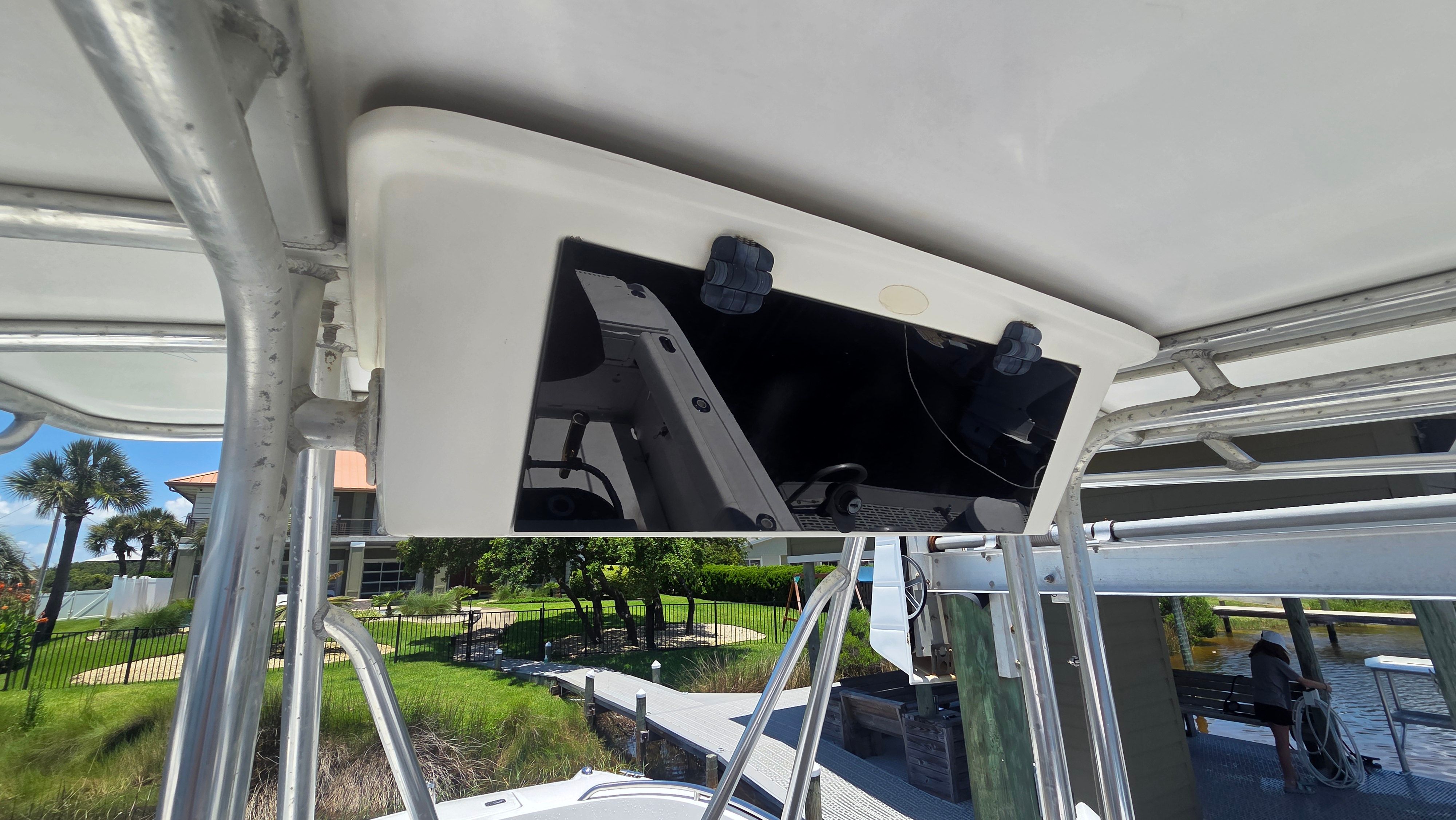 A boat with a white roof and a black panel underneath. It is situated in a marina.