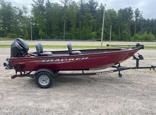 2025 Tracker Super Guide V-16 T boat on trailer, red color, parked outdoors.