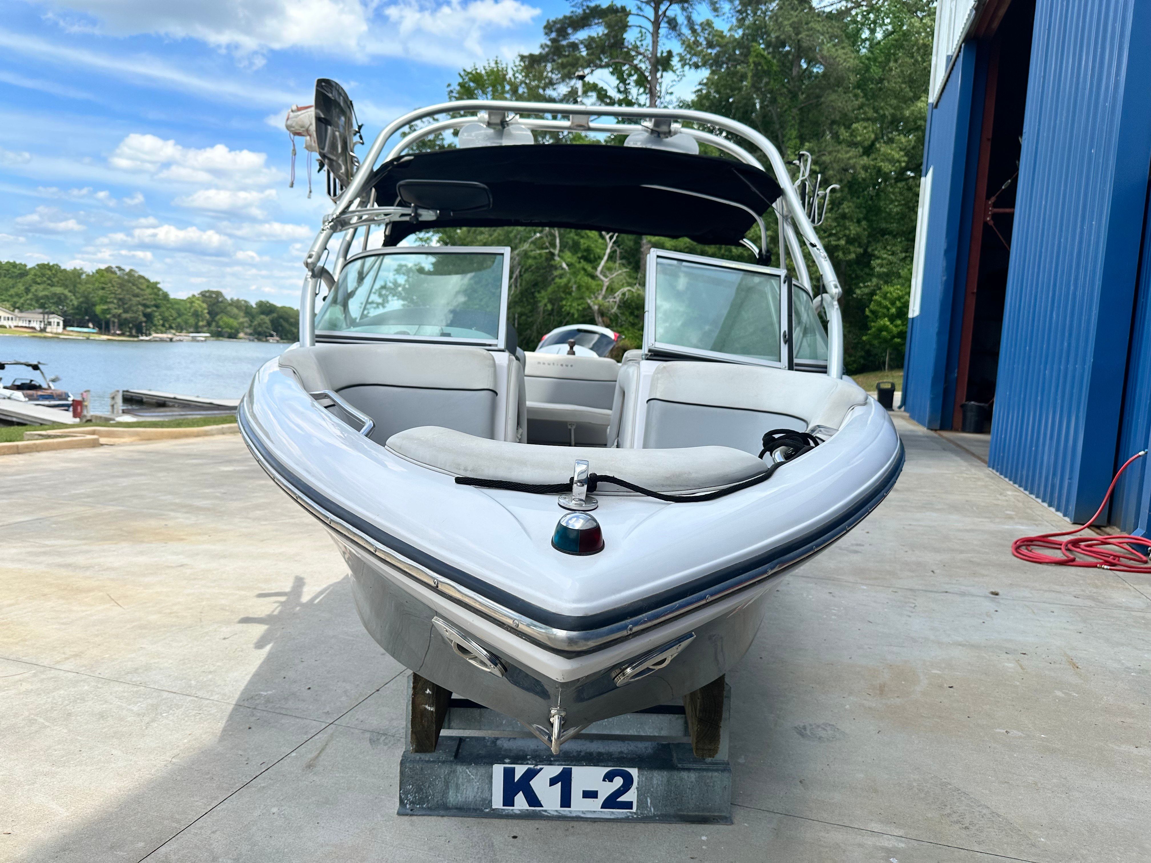 2007 Nautique SV 211 at the shore with trees in the background.