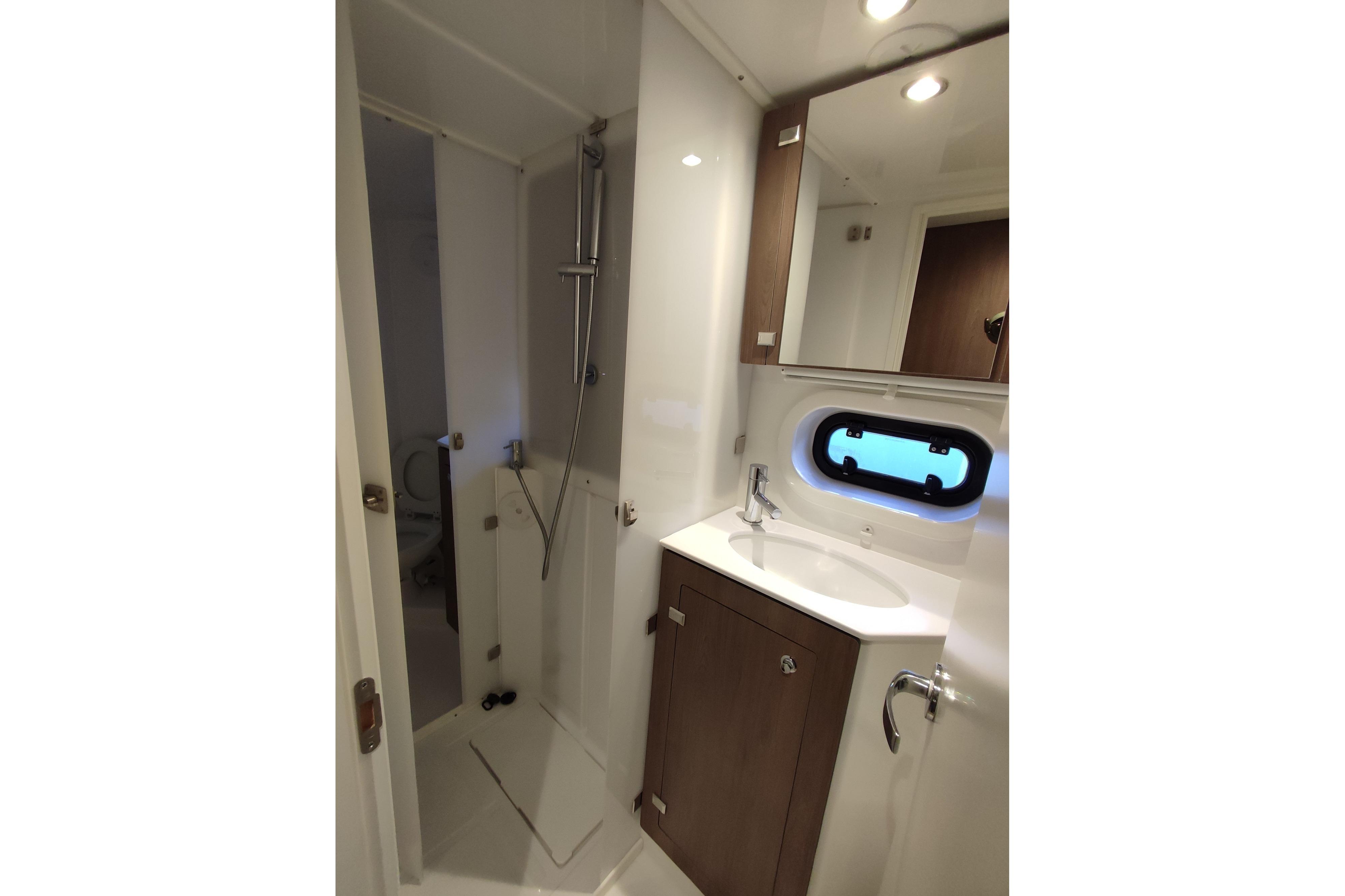 Modern bathroom in 2023 Bali 4.2 yacht with shower, sink, and porthole window.