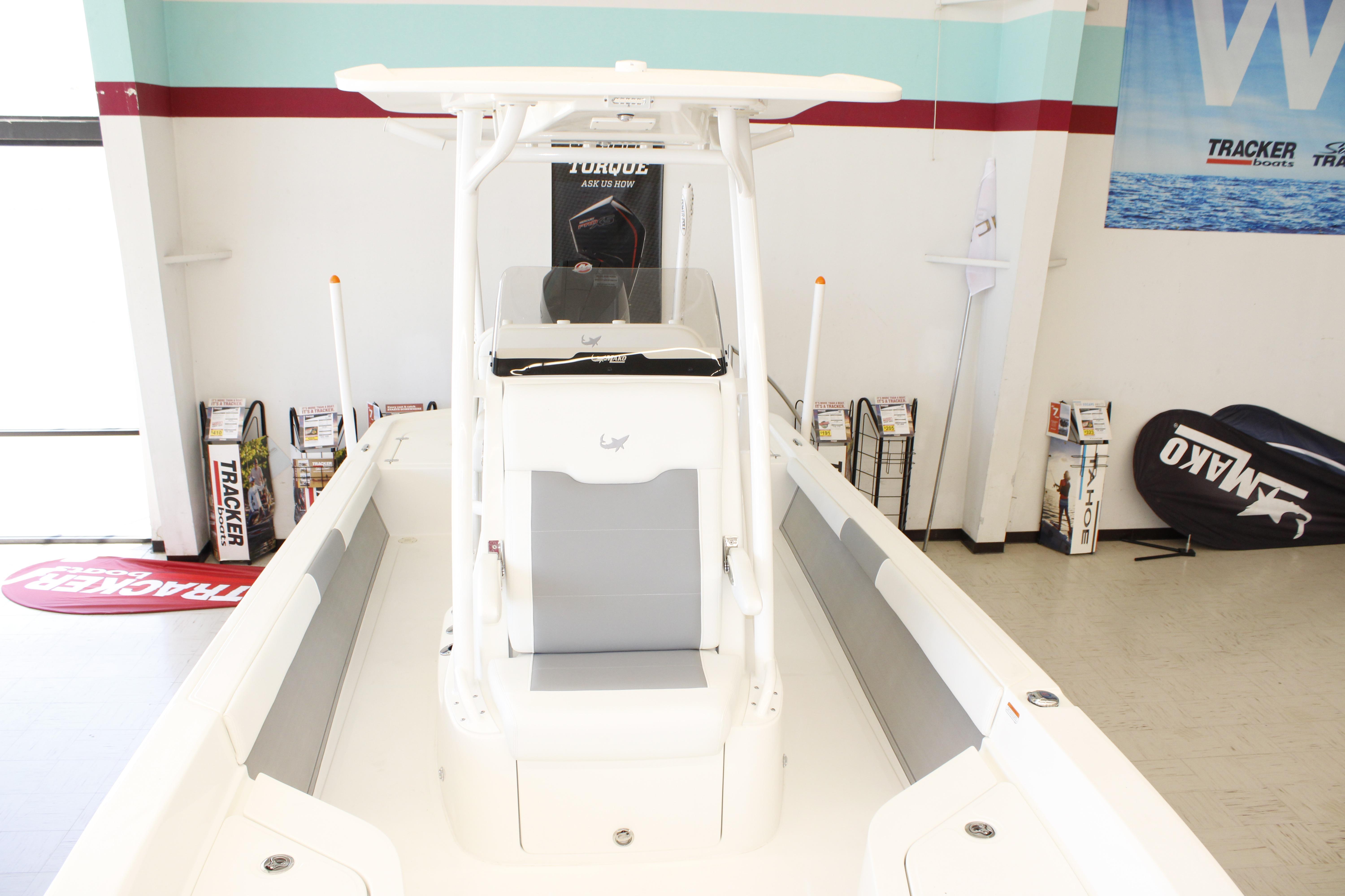 2026 Mako 24 APEX boat displayed in showroom with promotional materials.