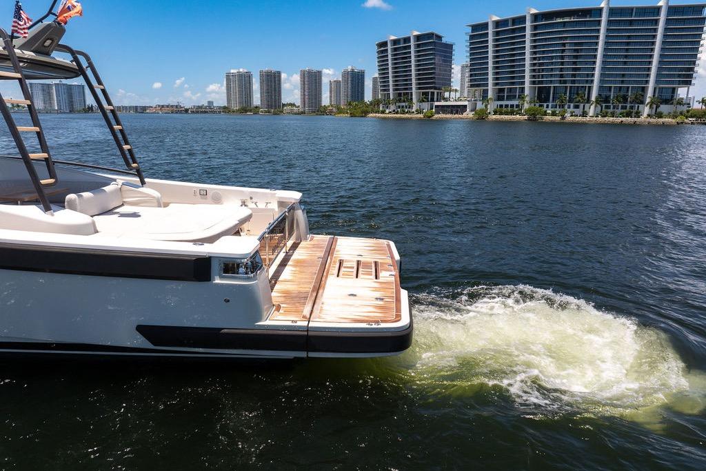 2021 Bluegame BG 42 yacht cruising near modern waterfront buildings.