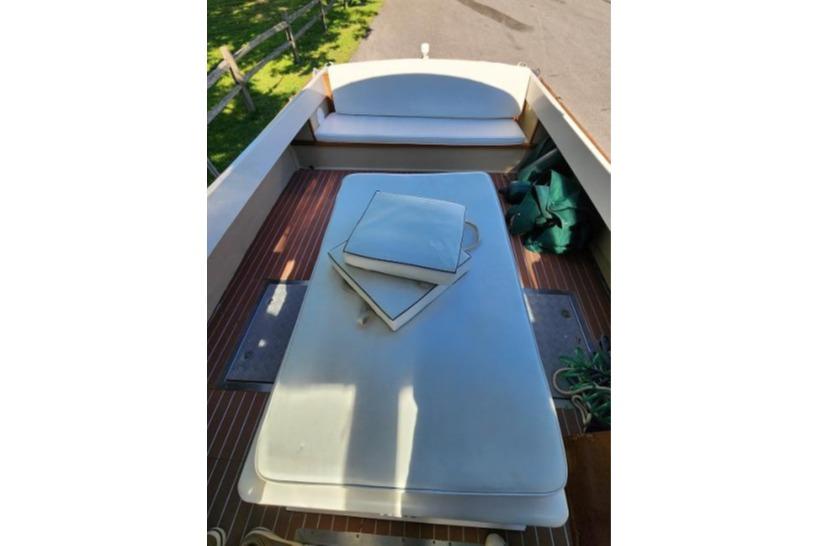 1985 Wasque Down East Cruiser interior with cushioned seating and wooden flooring.
