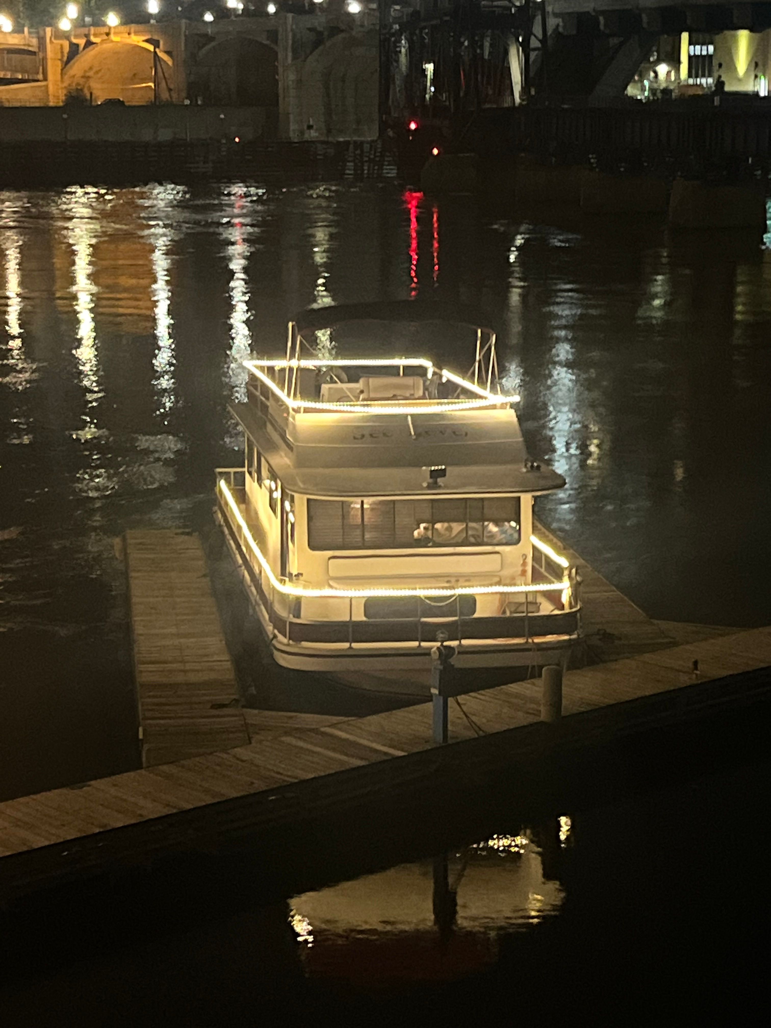 A lit-up houseboat docked at night on the water.