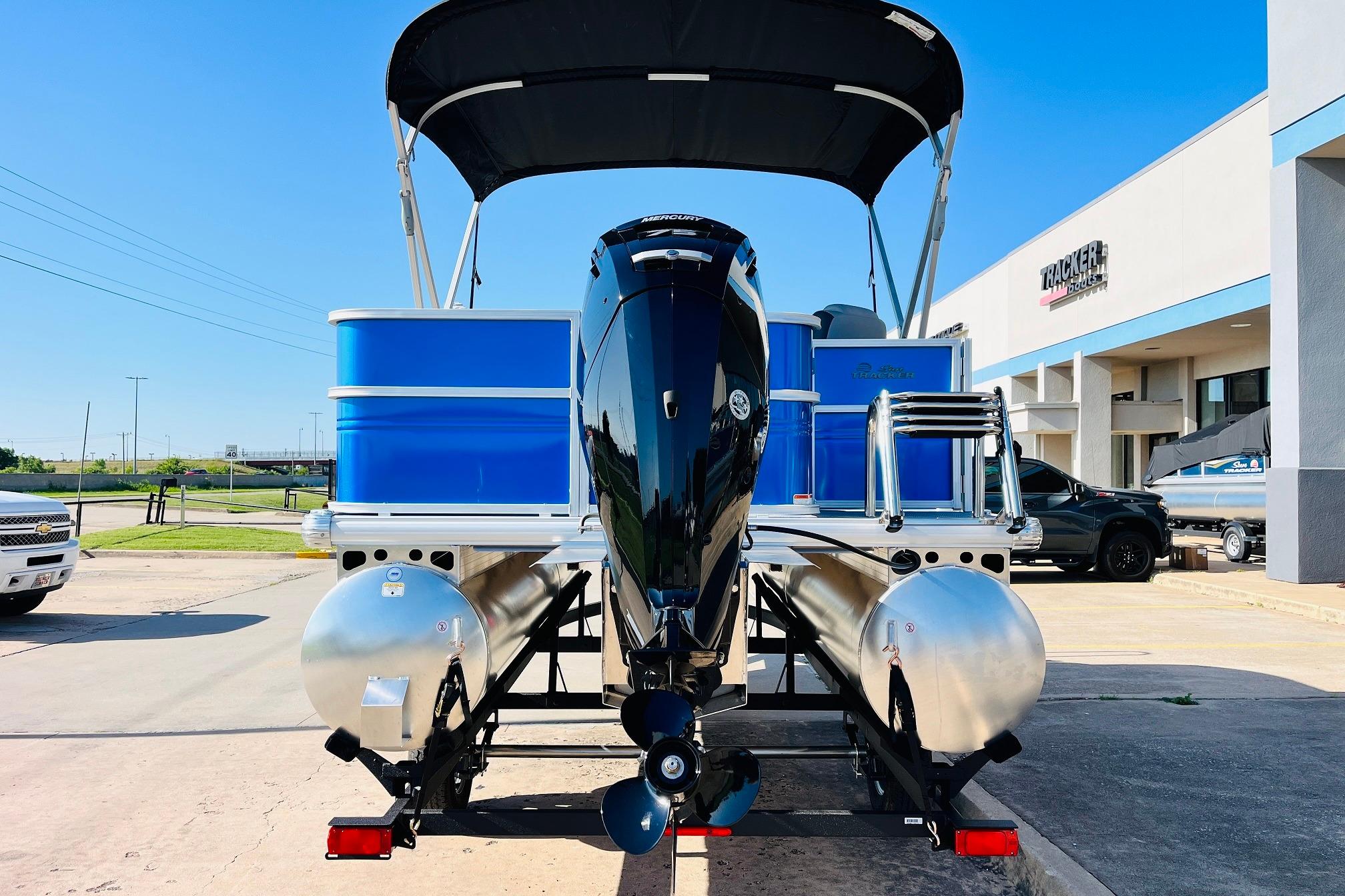 2026 Sun Tracker Party Barge 18 DLX pontoon boat with outboard motor, parked outdoors.