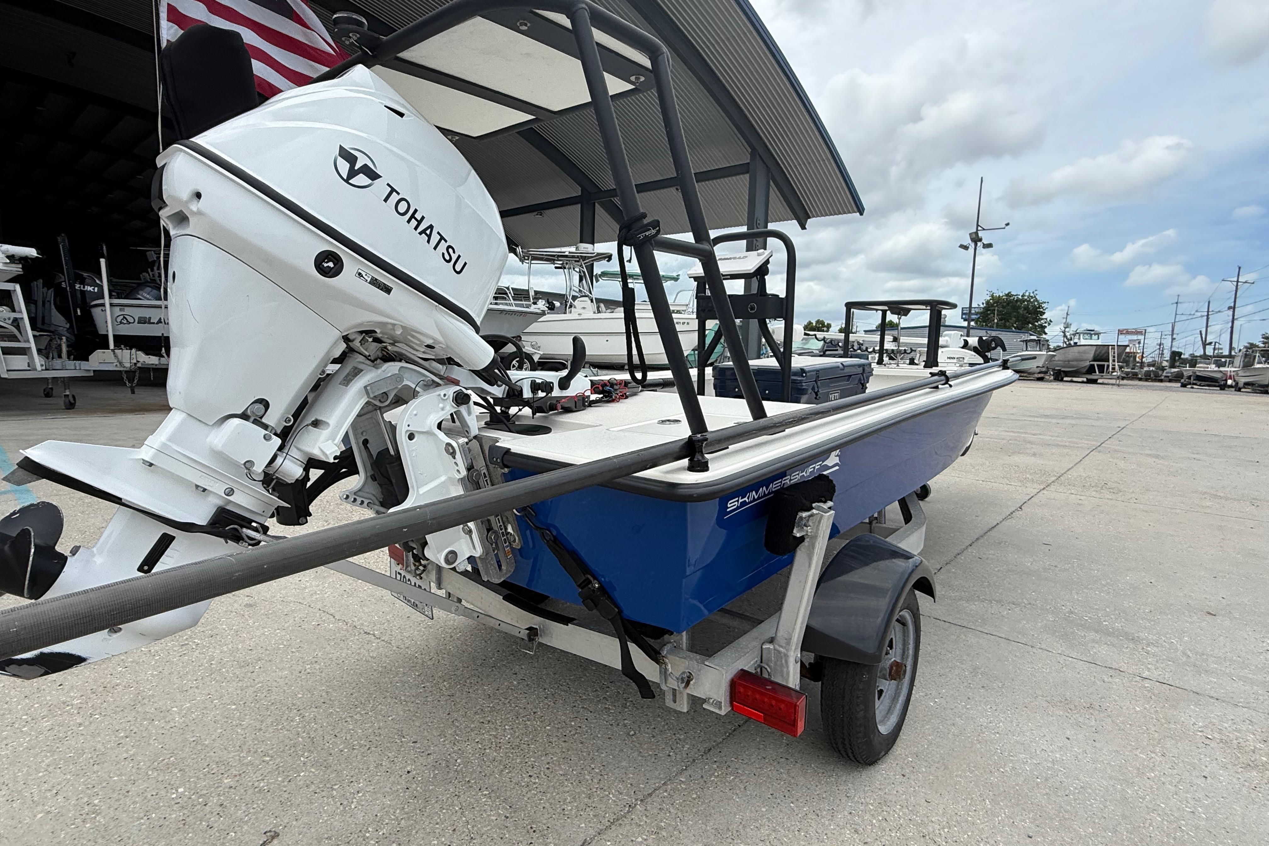 2020 Skimmer Skiff 14 boat with Tohatsu engine on a trailer, parked outdoors.