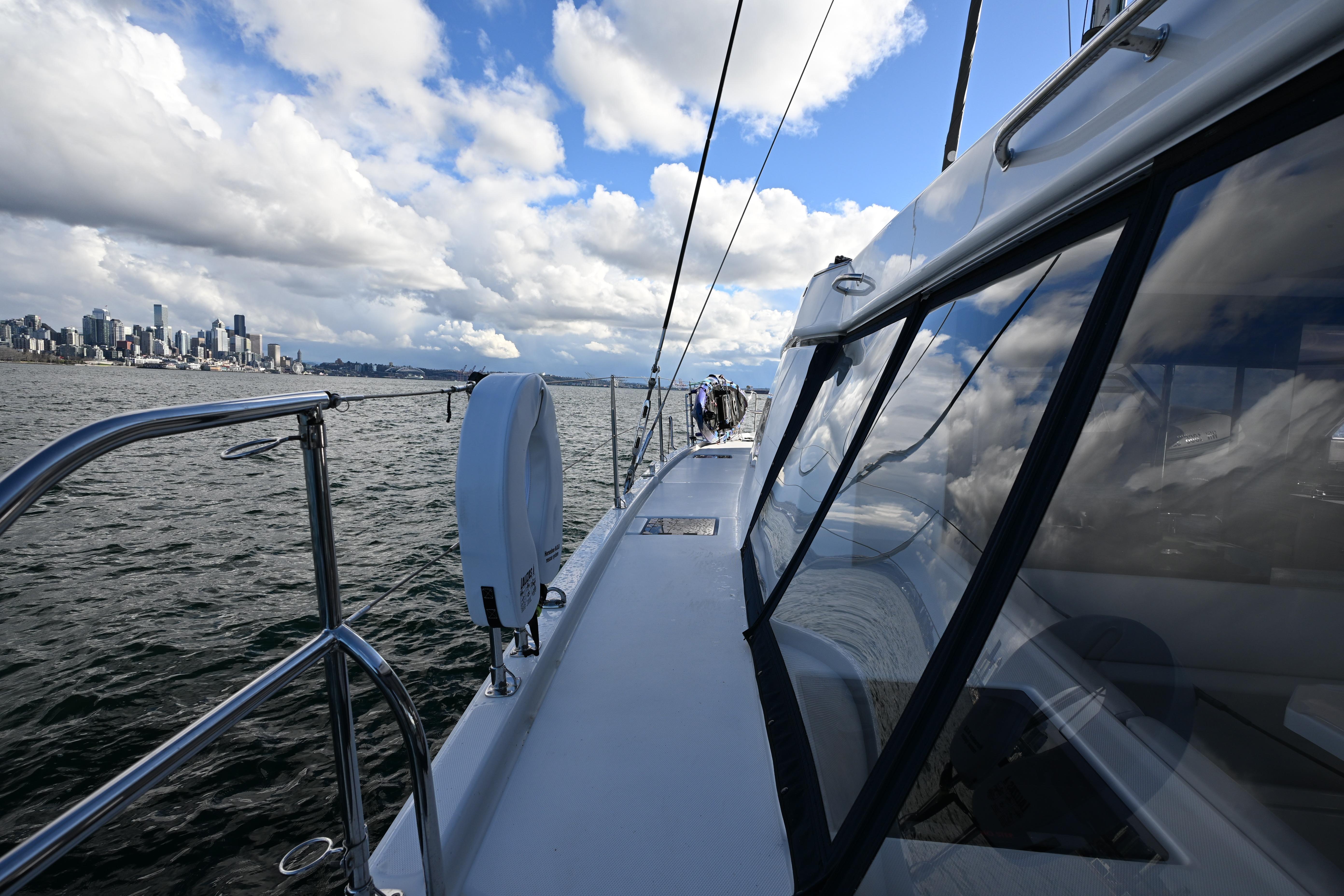 2020 Leopard 45 yacht sailing near city skyline under cloudy sky.
