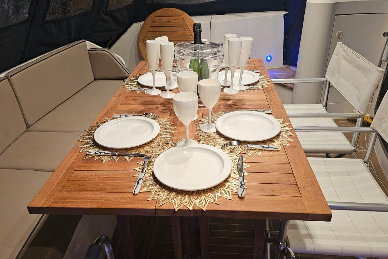 Elegant dining setup on Fairline Squadron 52 yacht, featuring wooden table and white tableware.