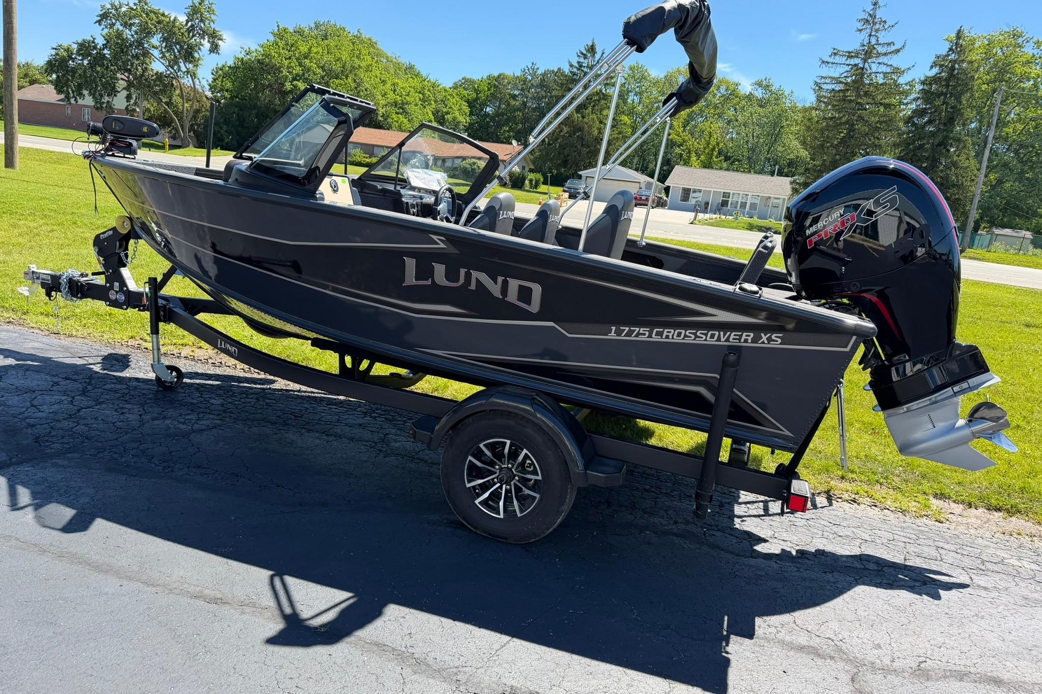 2027 Lund 1775 Crossover XS boat on trailer, parked outdoors on sunny day.
