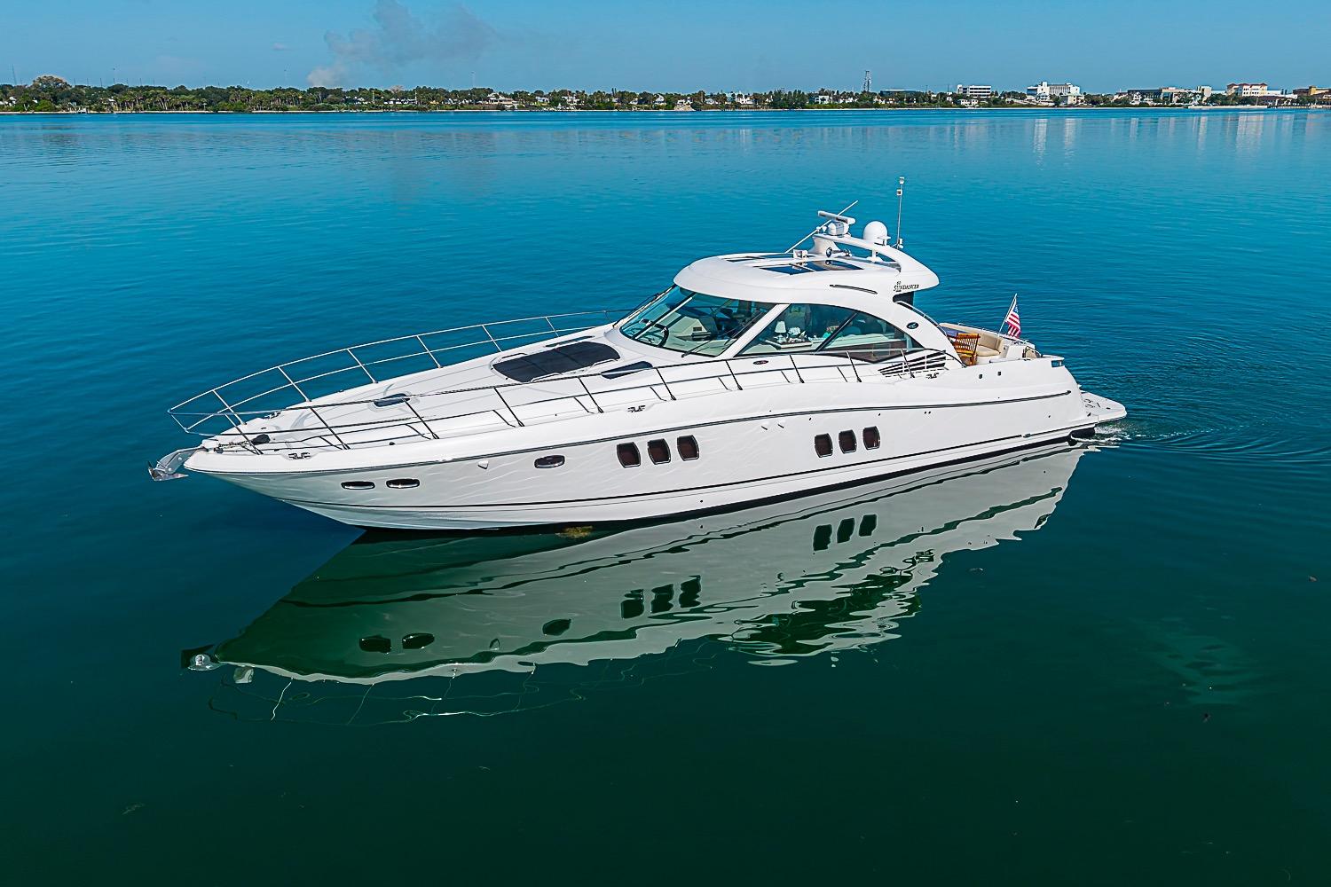 2008 Sea Ray 60 Sundancer yacht on calm blue water, reflecting the clear sky.