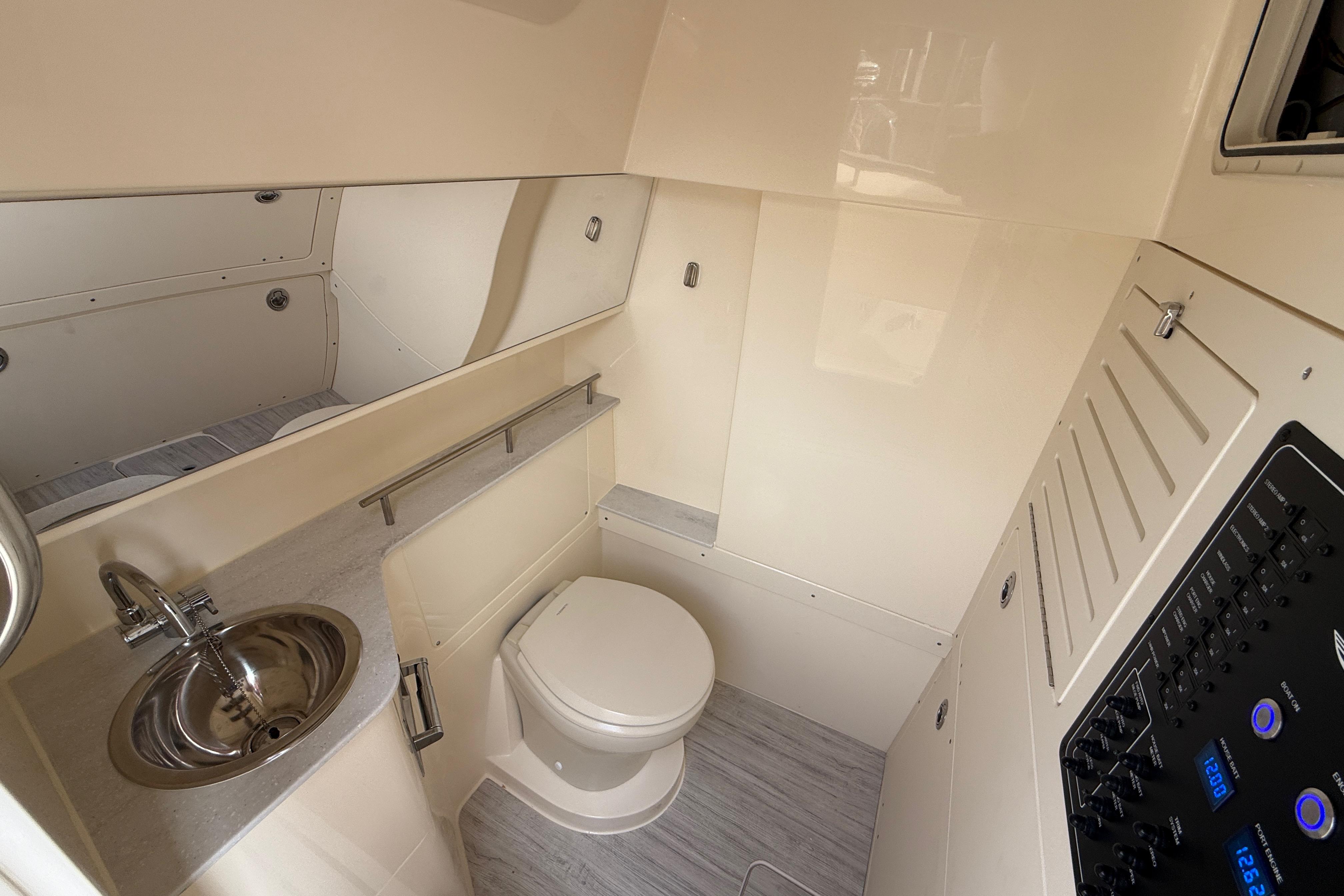 2026 Scout 288 LXF boat interior bathroom with sink, toilet, and control panel.