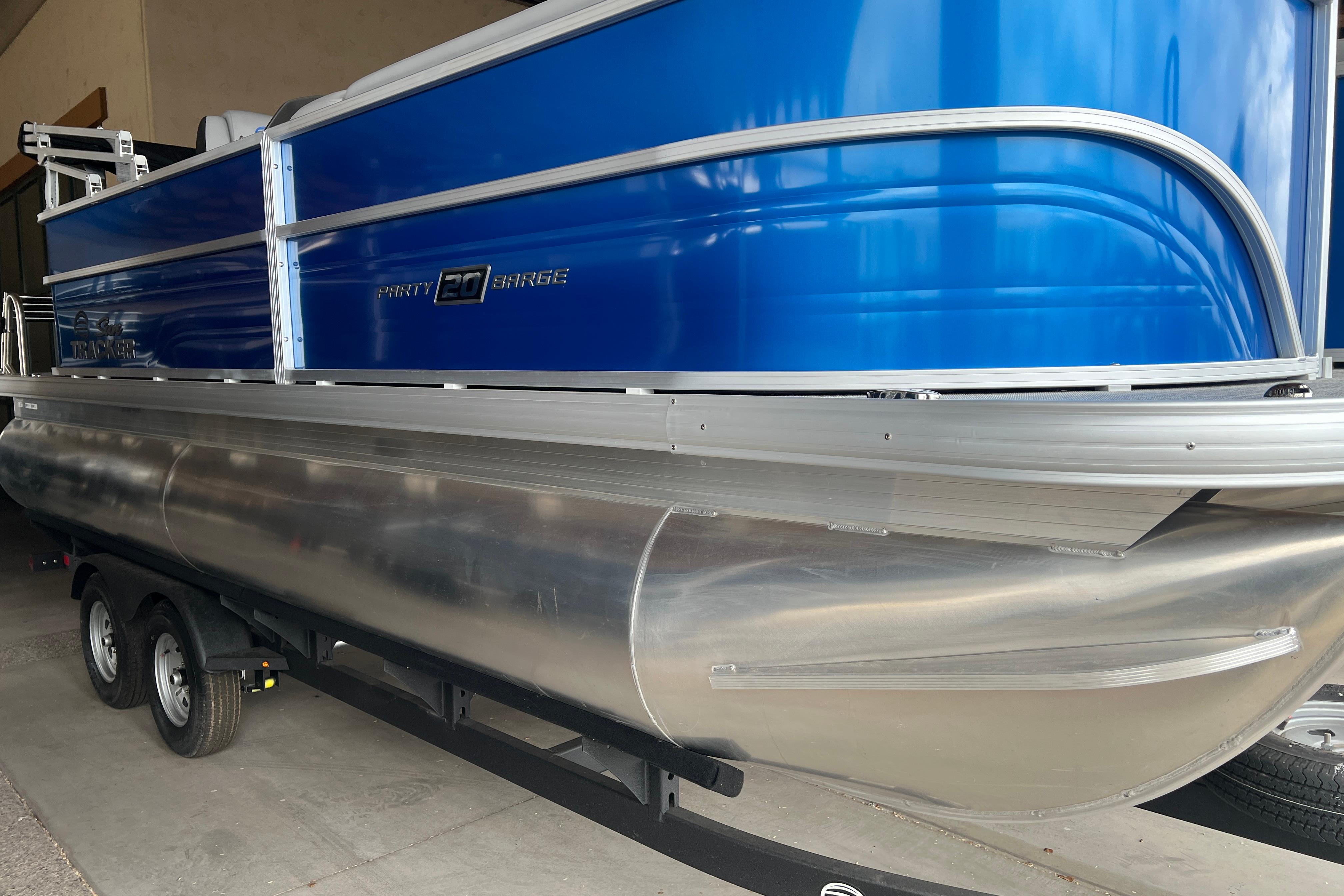 2026 Sun Tracker Party Barge 20 DLX pontoon boat with blue exterior and dual-axle trailer.