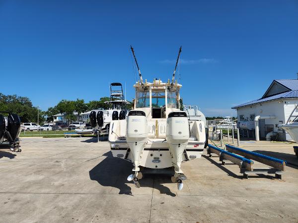 2005 Pursuit 3070 Offshore Center Console boat with dual outboard engines, parked on concrete.