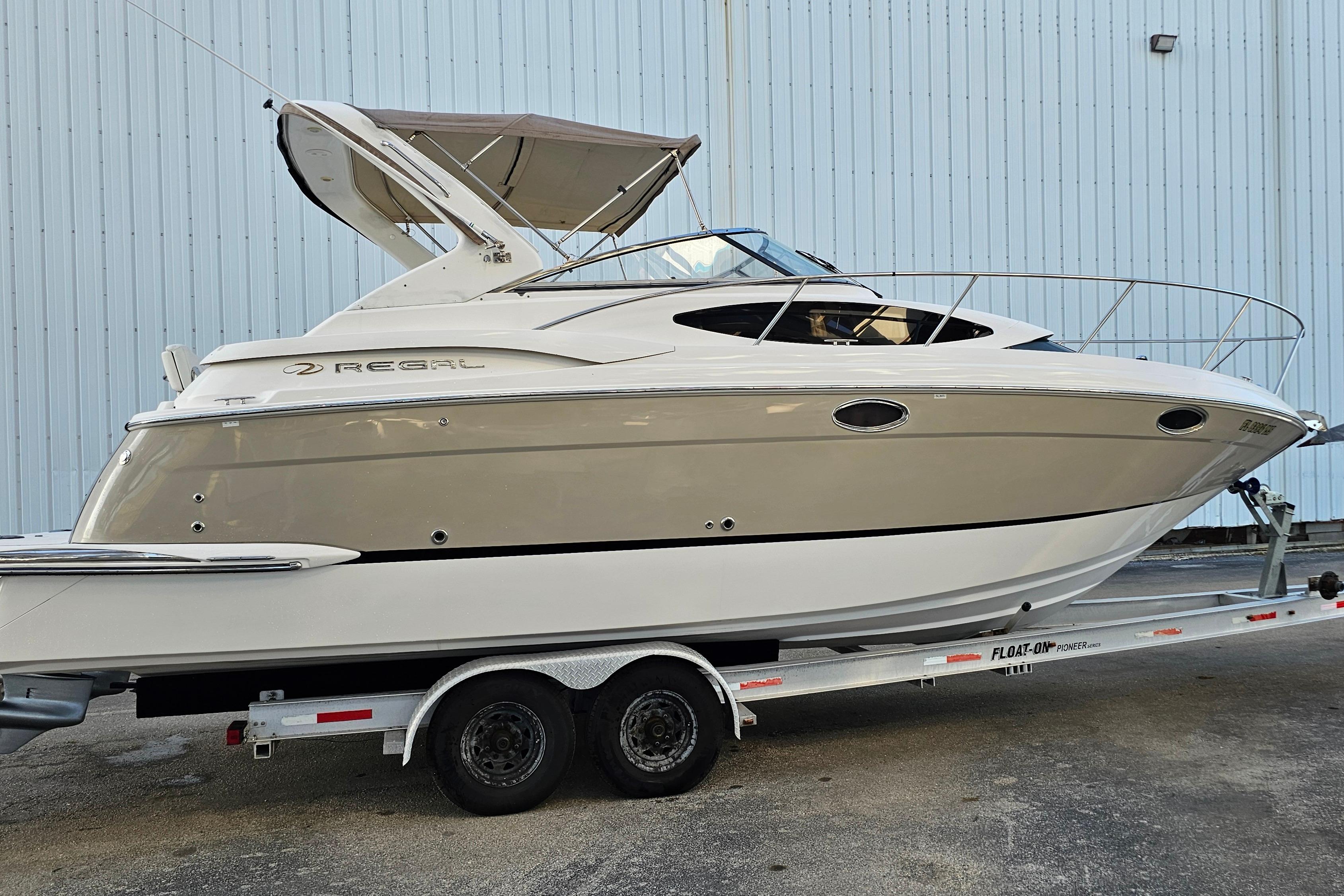 2005 Regal 3060 Window Express boat on trailer, parked near a building.