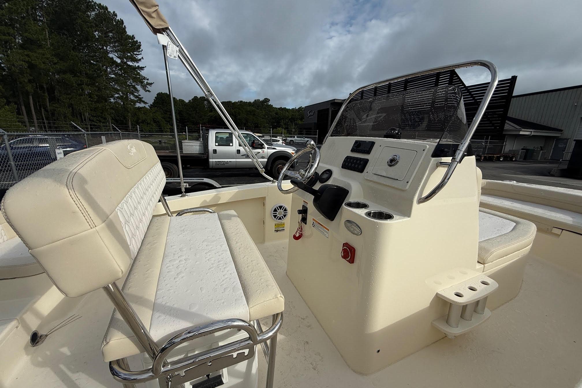 2026 Scout 188 Sportfish boat interior with steering console and seating, parked outdoors.