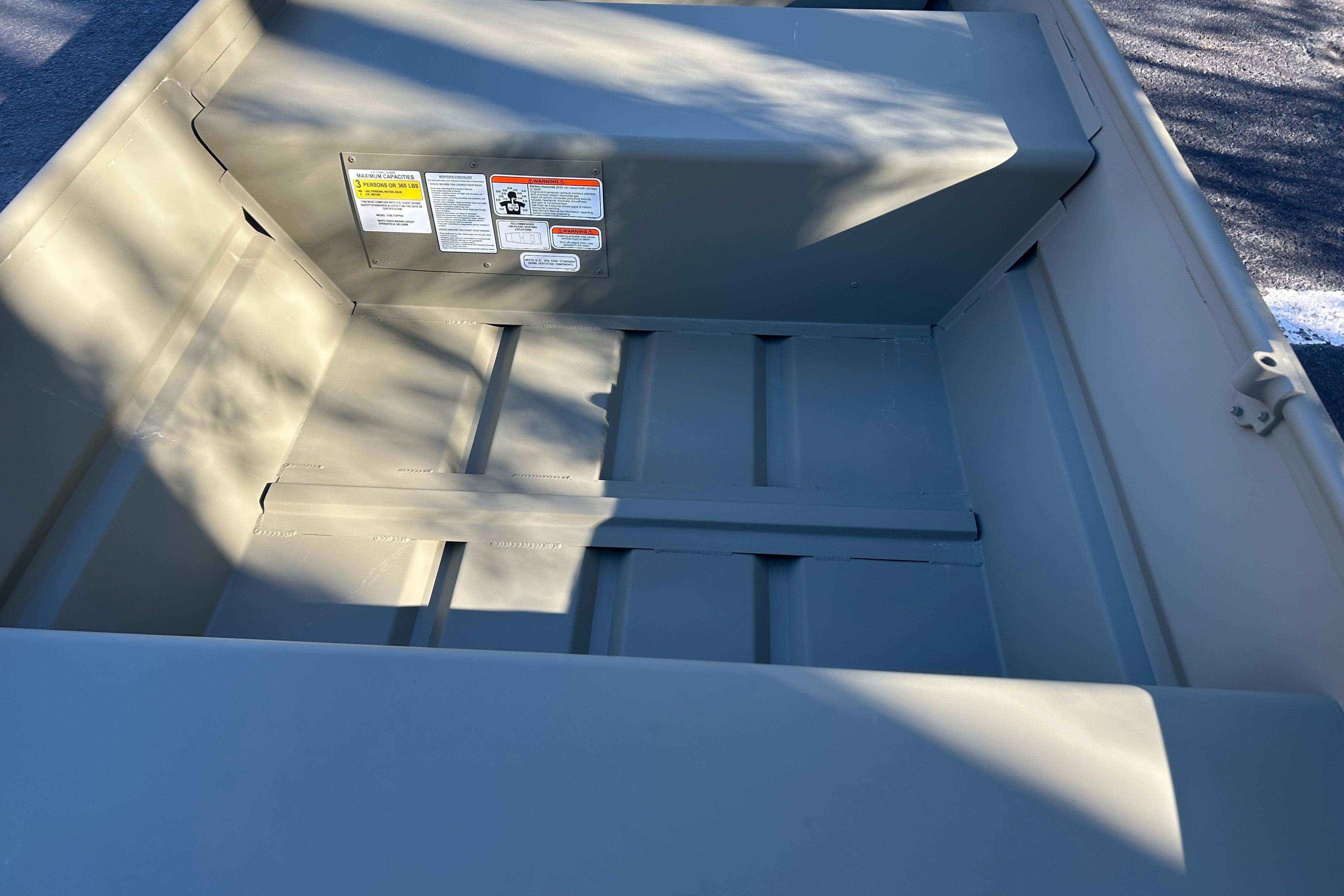 2026 Tracker Grizzly 12 Jon boat interior with safety labels and shadow patterns.