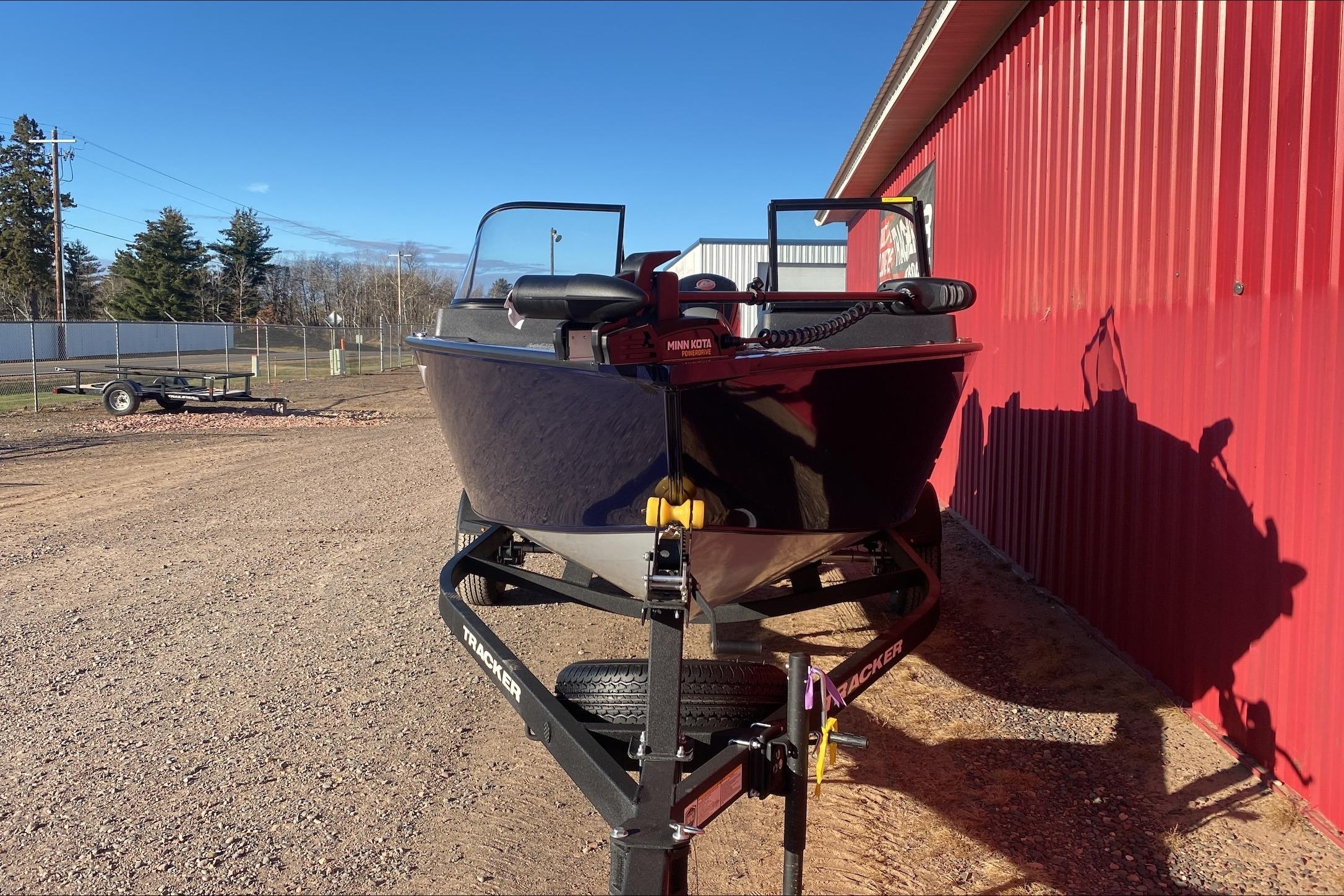 2026 Tracker Pro Guide V-175 WT boat on trailer beside red building.
