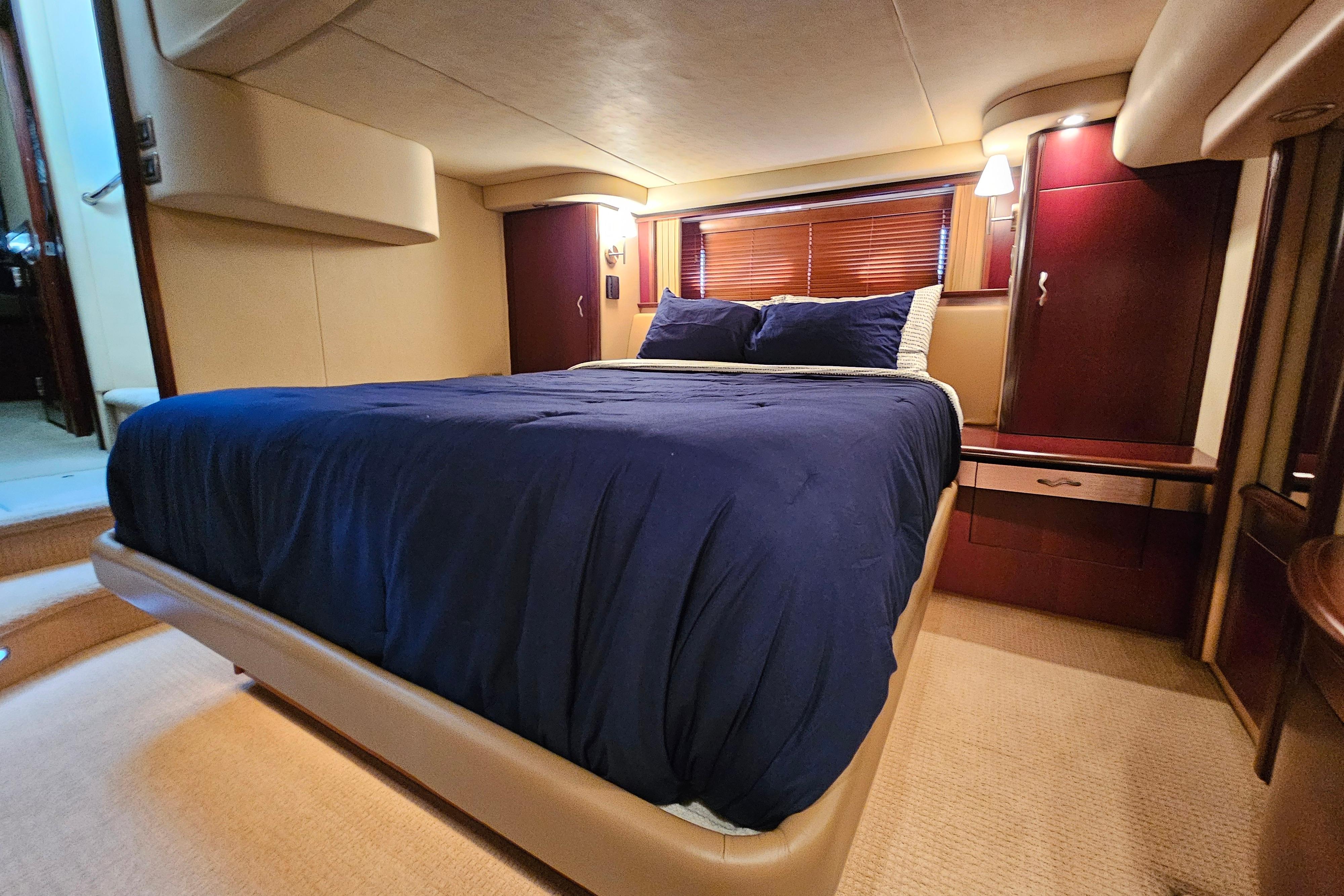 Luxurious bedroom interior of 2006 Sea Ray 580 Sedan Bridge yacht with blue bedding.