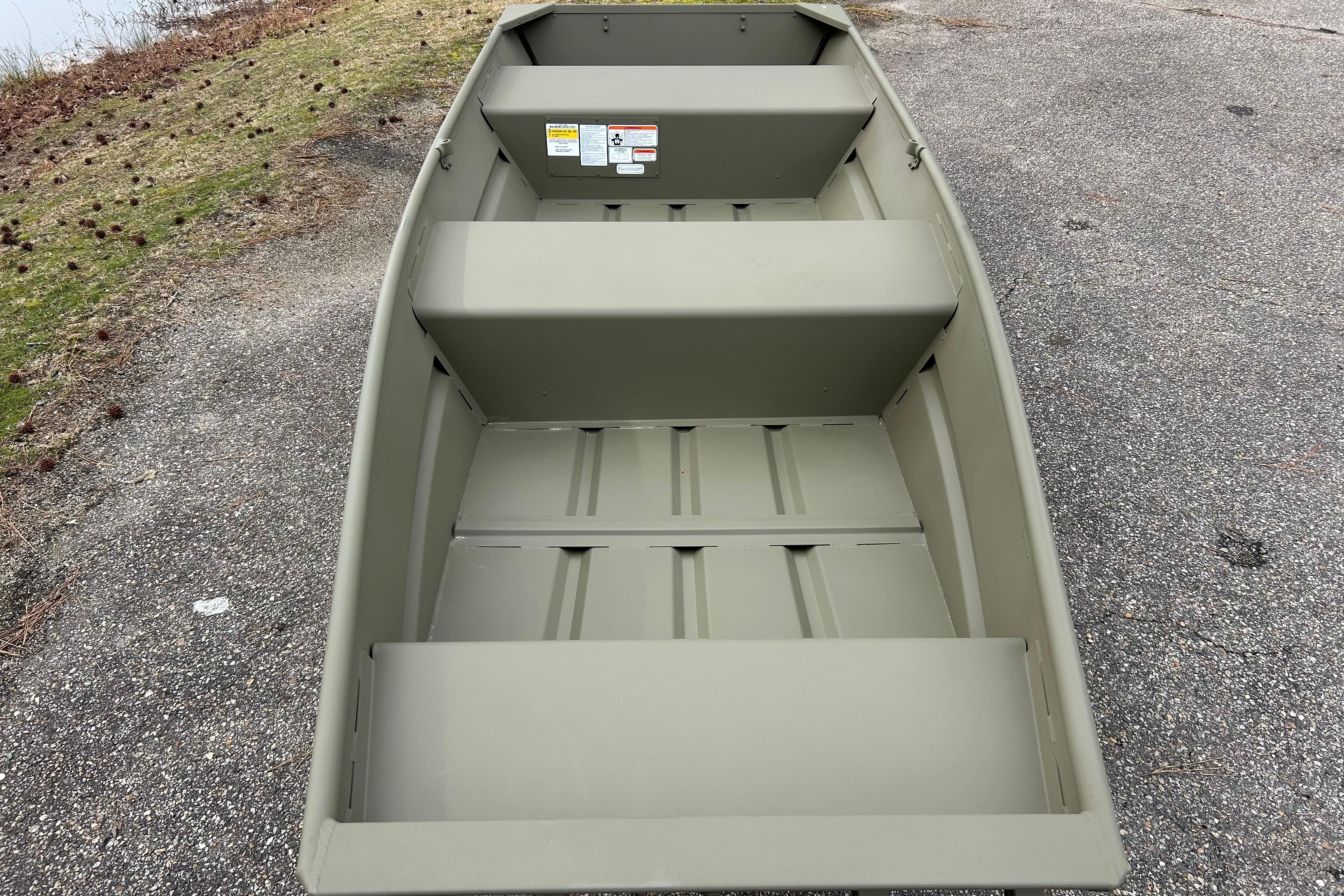 2026 Tracker Grizzly 14 Jon boat on a paved surface near grassy area.