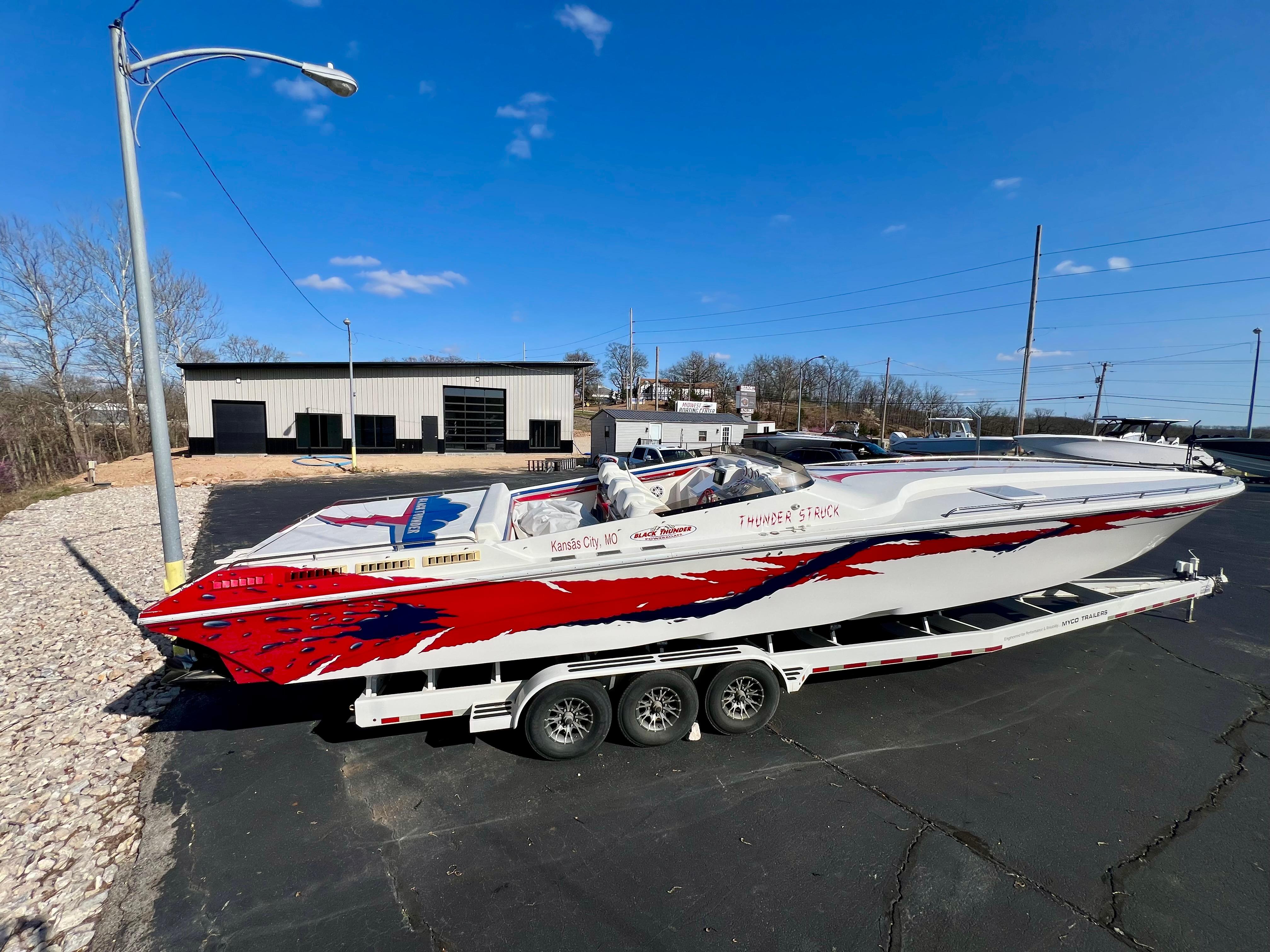 1999 Black Thunder 430 Flat Deck boat with red and blue graphics on a trailer.