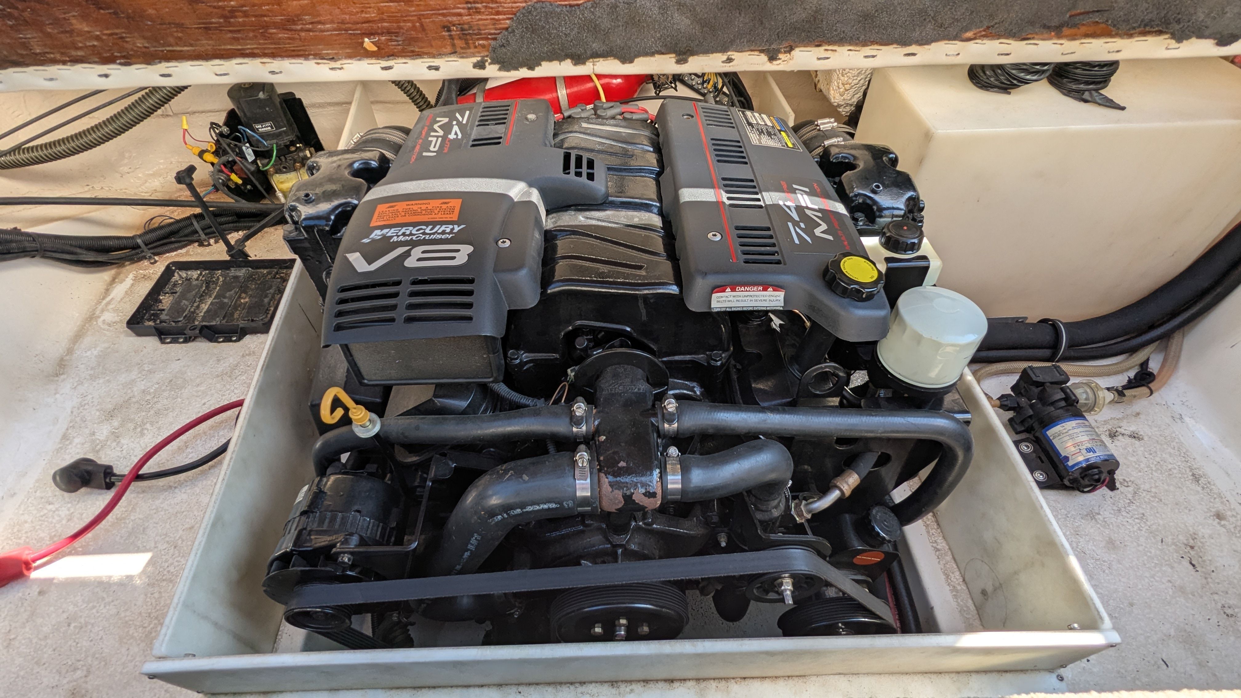 A Mercury V8 engine in a boat's engine compartment, surrounded by cables and hoses.