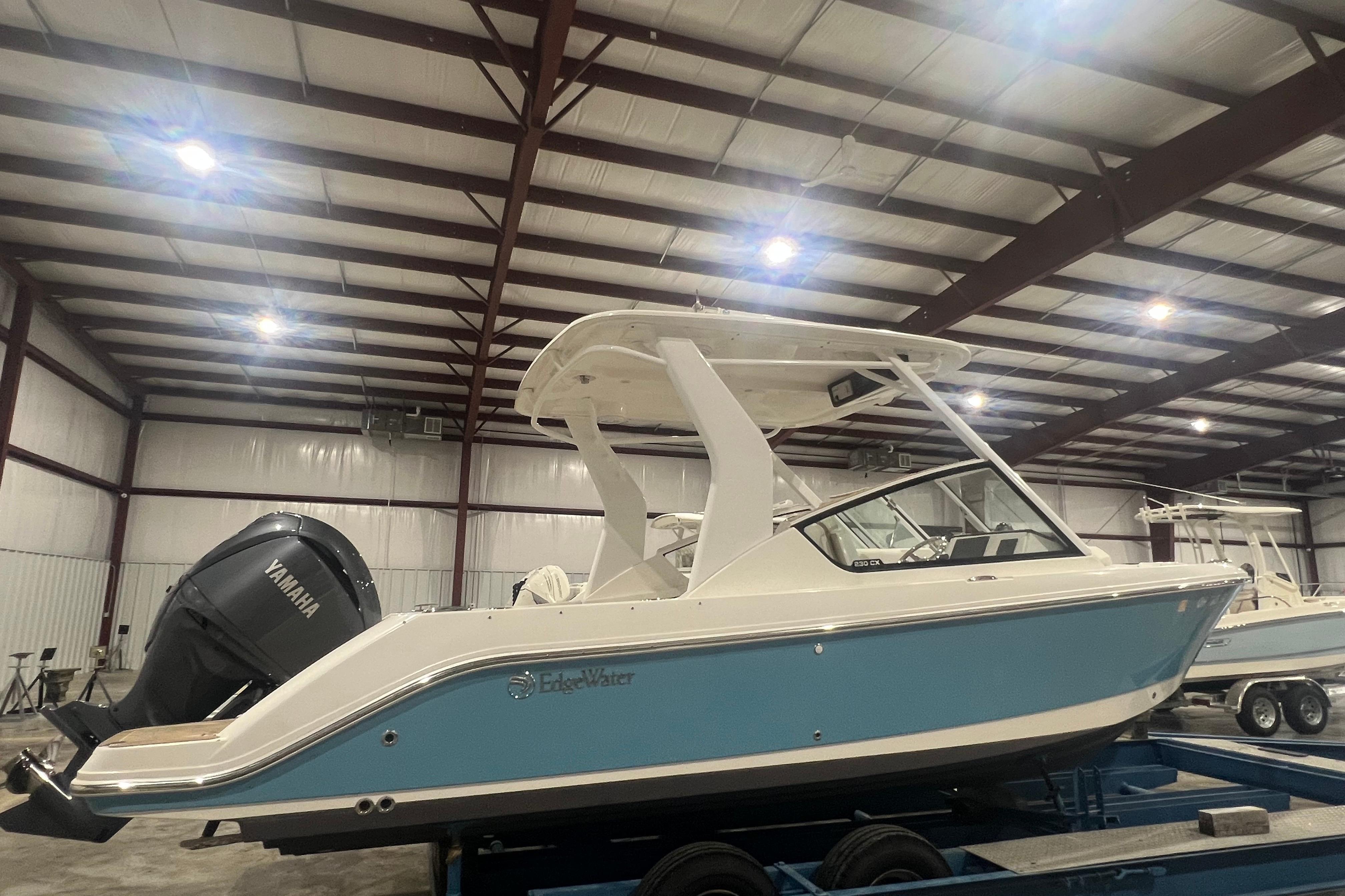 2023 Edgewater 230CX Crossover boat in a warehouse, featuring a Yamaha engine.