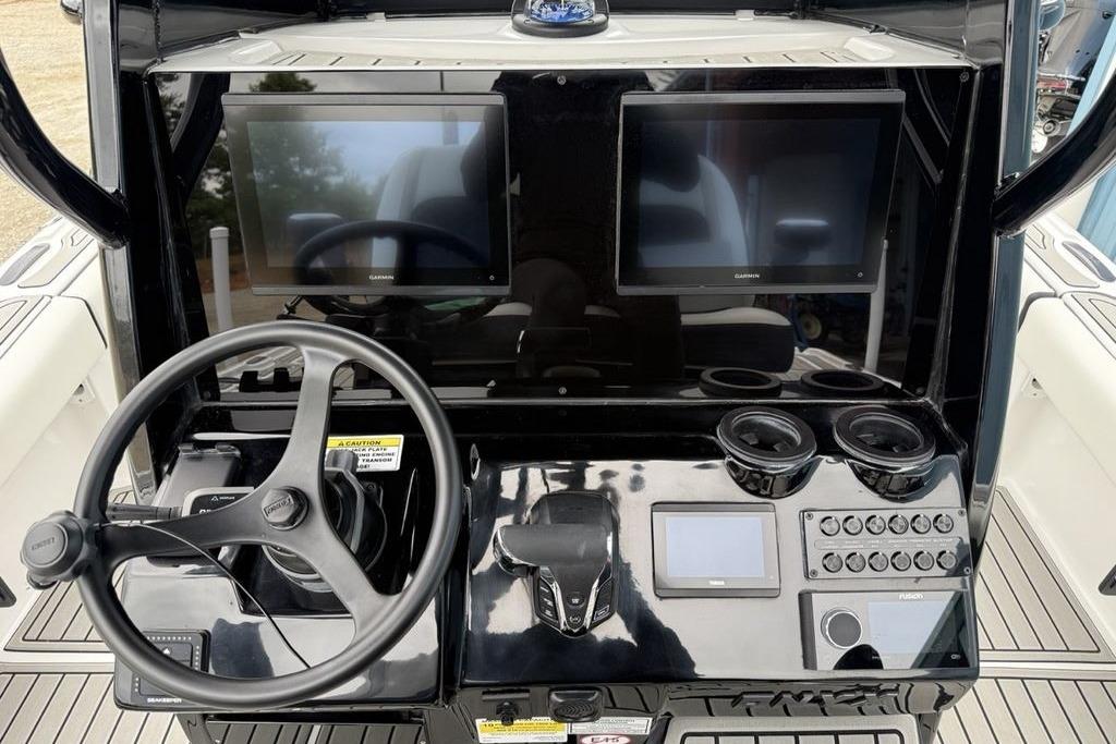 Steering console of 2026 Tidewater 2500 Carolina Bay boat with dual screens and controls.